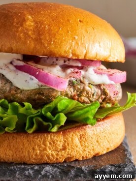 Juicy lamb kofta burger served on a toasted bun with fresh toppings and a dollop of creamy tzatziki sauce.