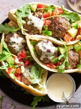 Warm pita pockets generously stuffed with savory Mediterranean beef meatballs, crisp salad greens, and a drizzle of creamy tahini sauce.