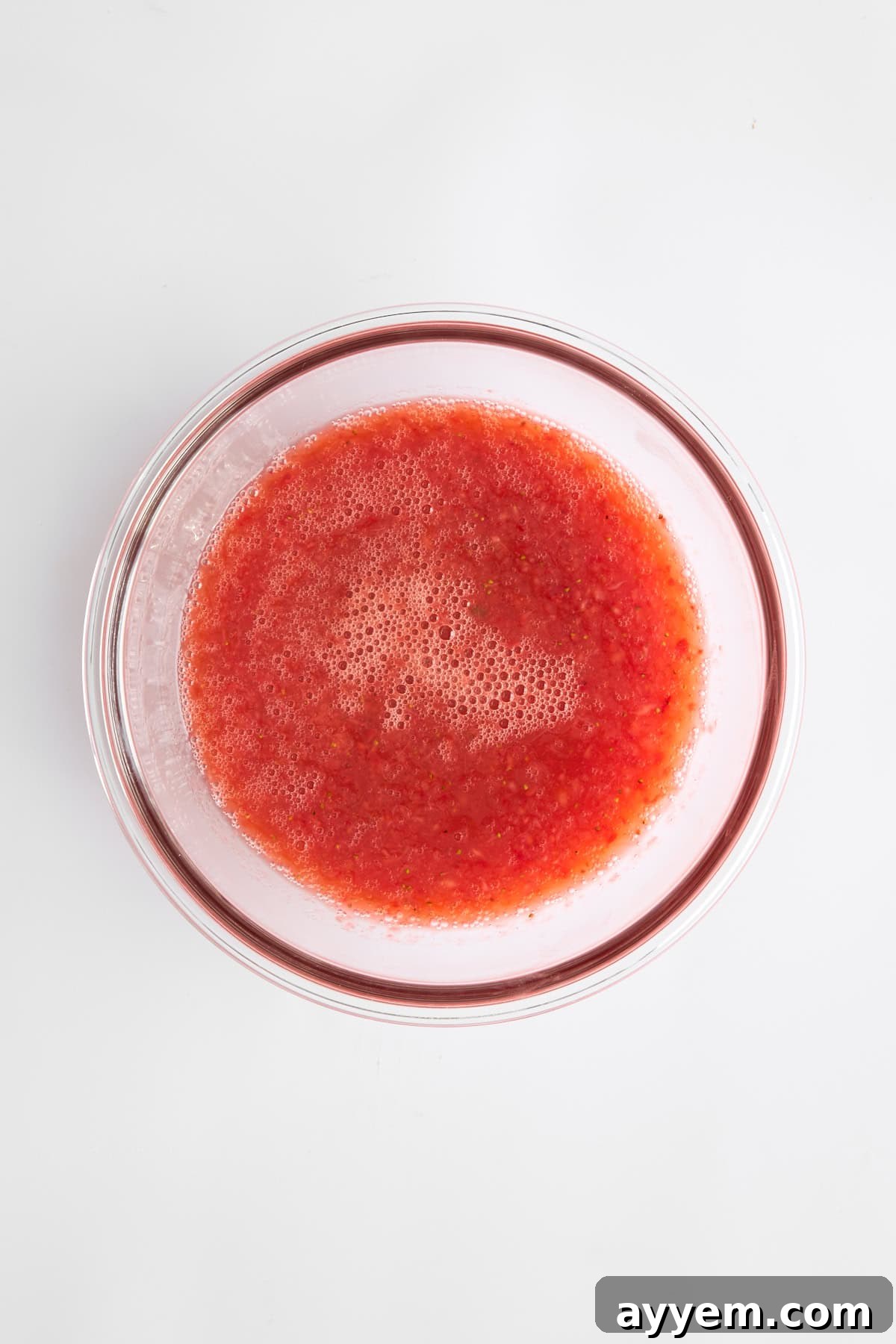 A close-up shot of the rich, smooth strawberry puree resting in a bowl, showcasing its bright, natural color.