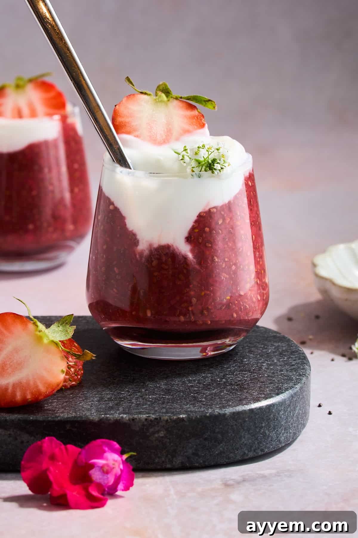 A jar of strawberry chia pudding topped with yogurt and a fresh strawberry slice, ready to be enjoyed.
