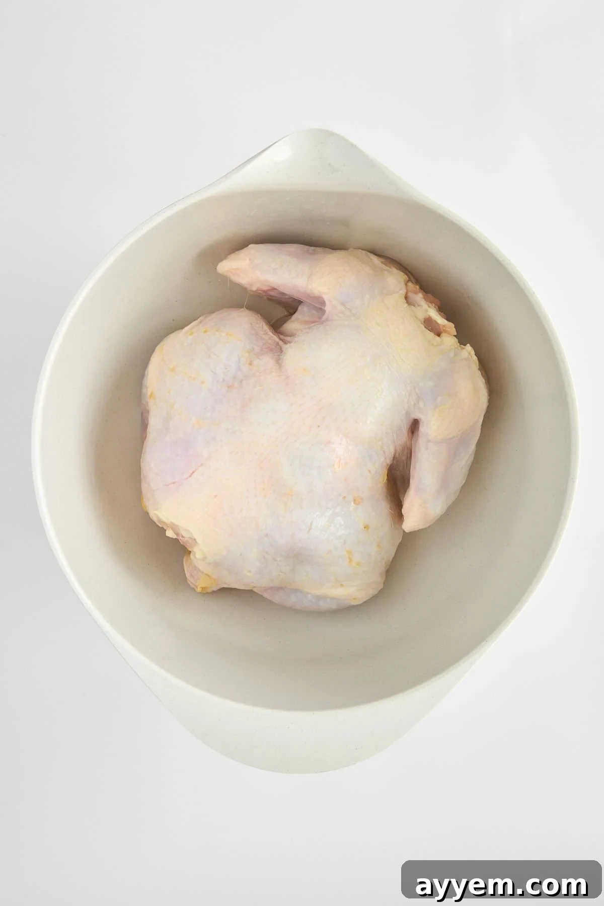 A raw whole chicken ready for seasoning.