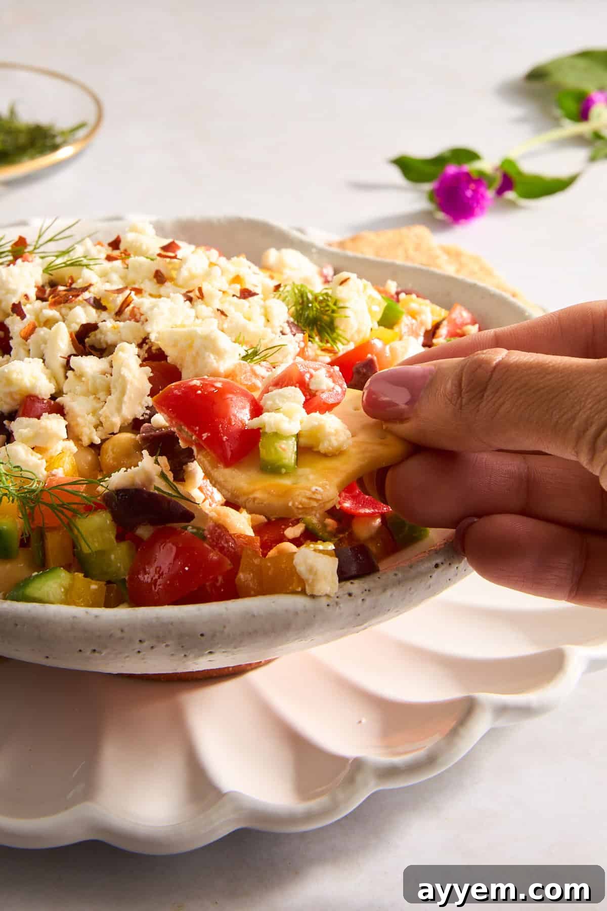 A pita chip being dipped into a bowl of Mediterranean dip.