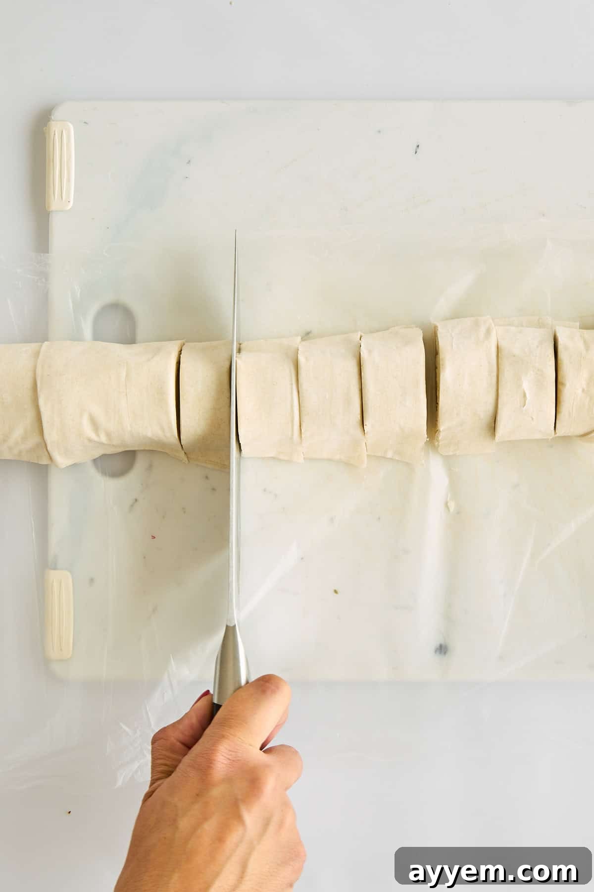 Unbaked hot honey feta phyllo rolls, neatly sliced and ready for the oven, displaying their layered texture.