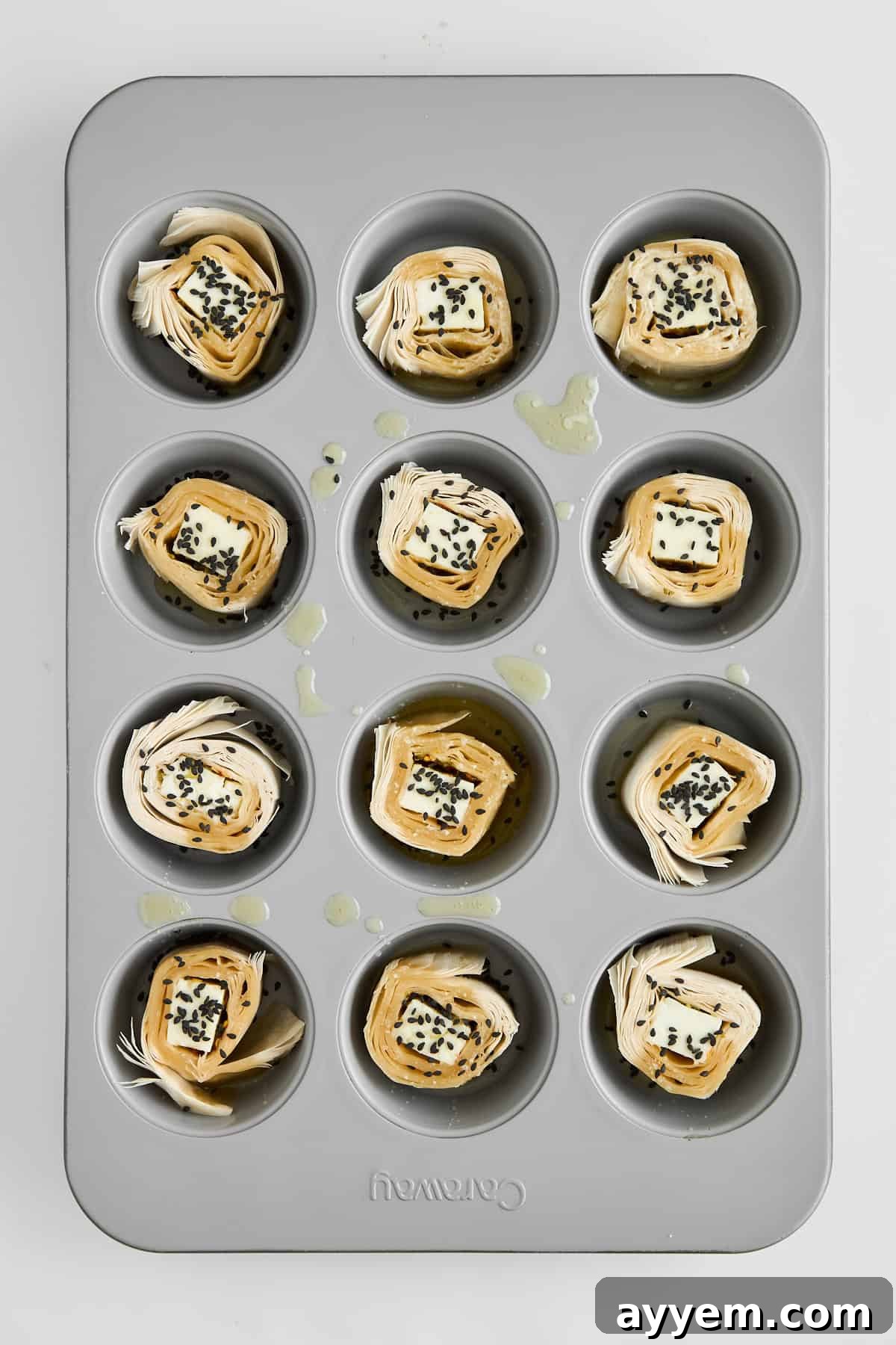 Golden-brown Hot Honey Feta Phyllo Rolls baked to perfection in a muffin pan, glistening with butter.