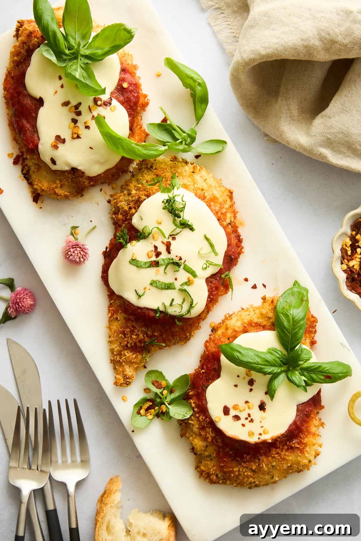 Baked chicken parmesan pieces on a platter, garnished with fresh basil, showcasing a golden crust and melted cheese.