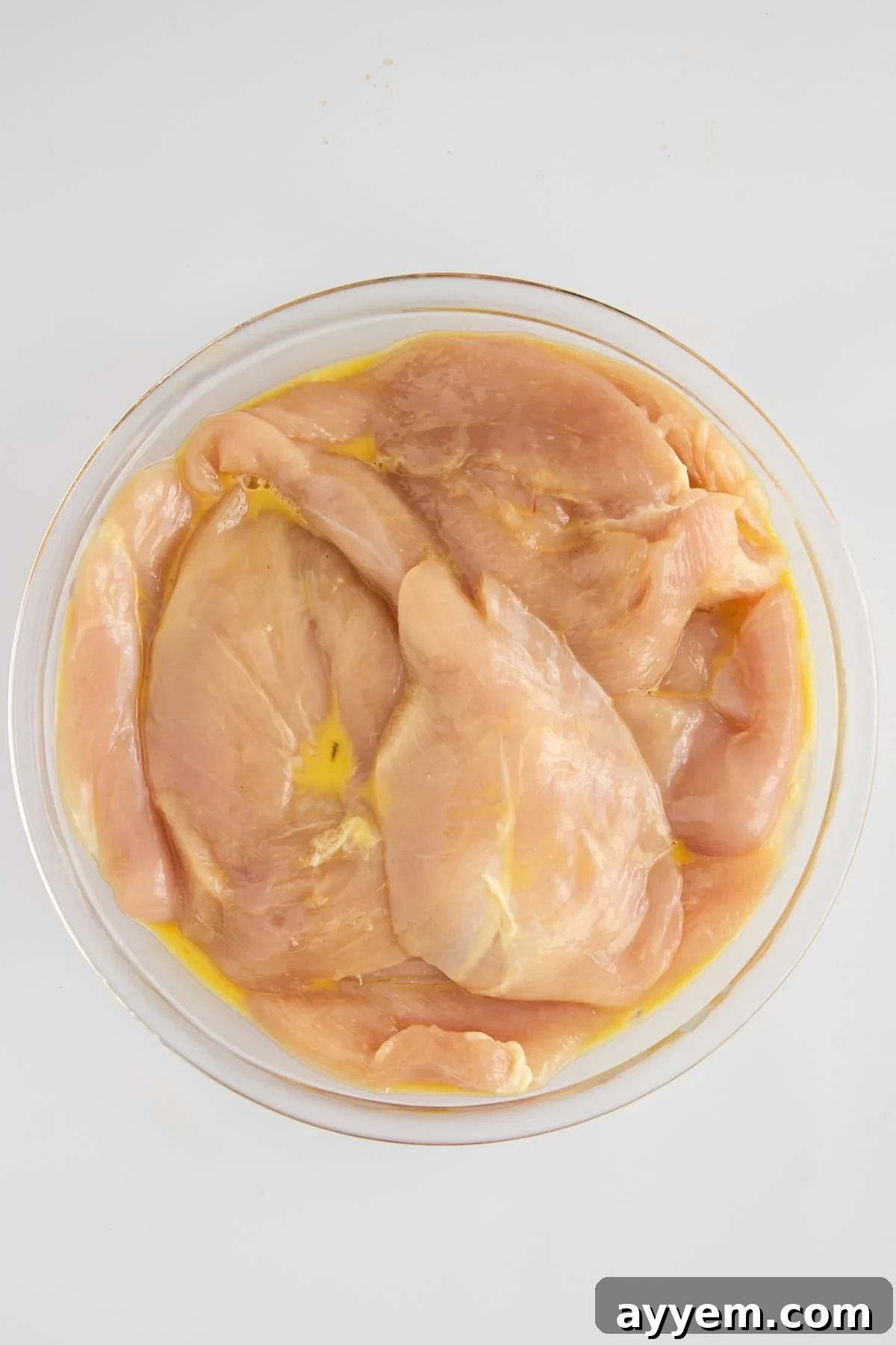 Raw chicken being coated in egg wash for oven frying.