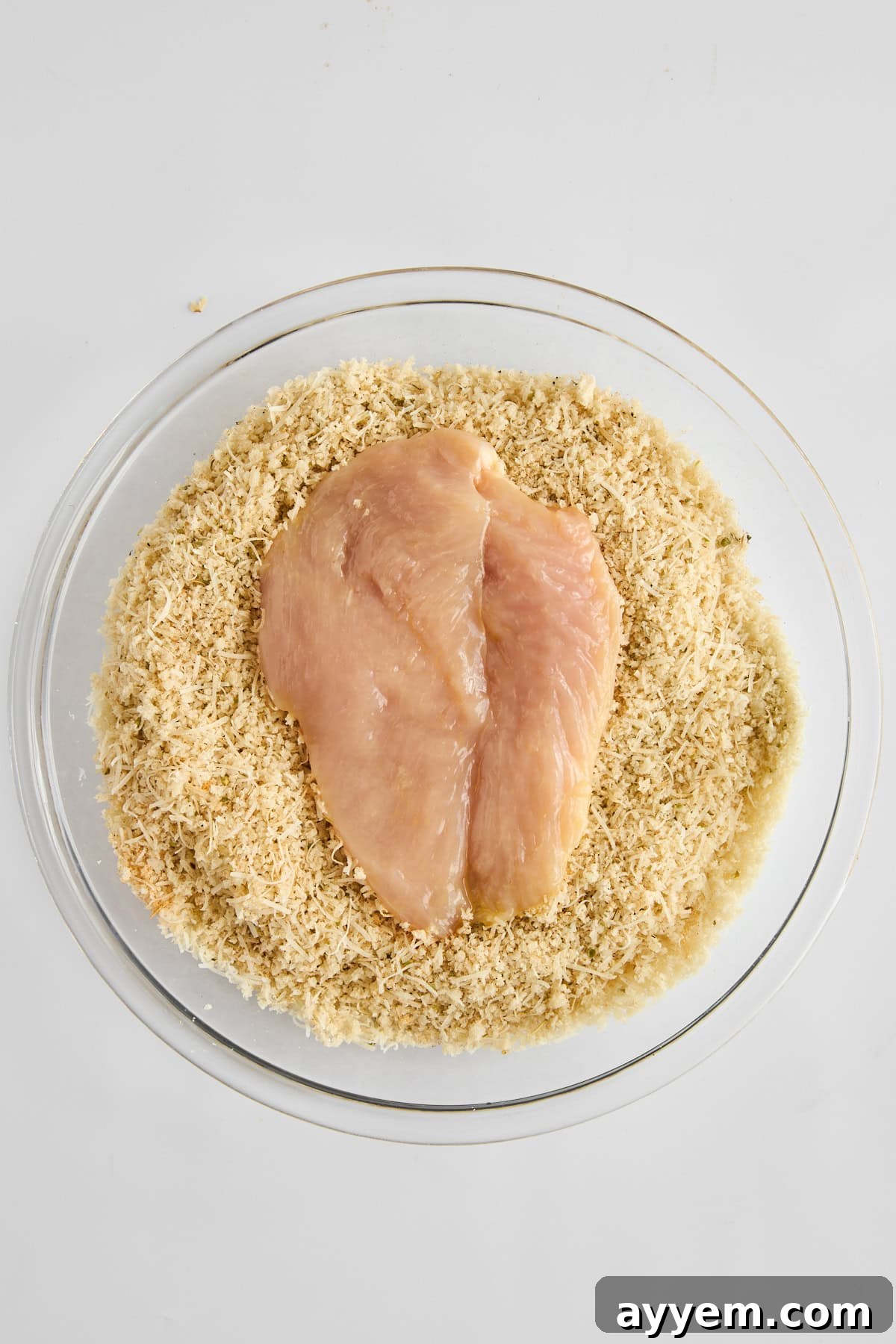 Raw chicken pieces being breaded with panko mixture.