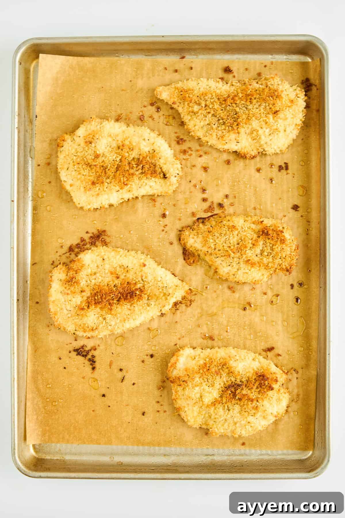 Golden Easy Oven Fried Chicken pieces cooling on a baking sheet.