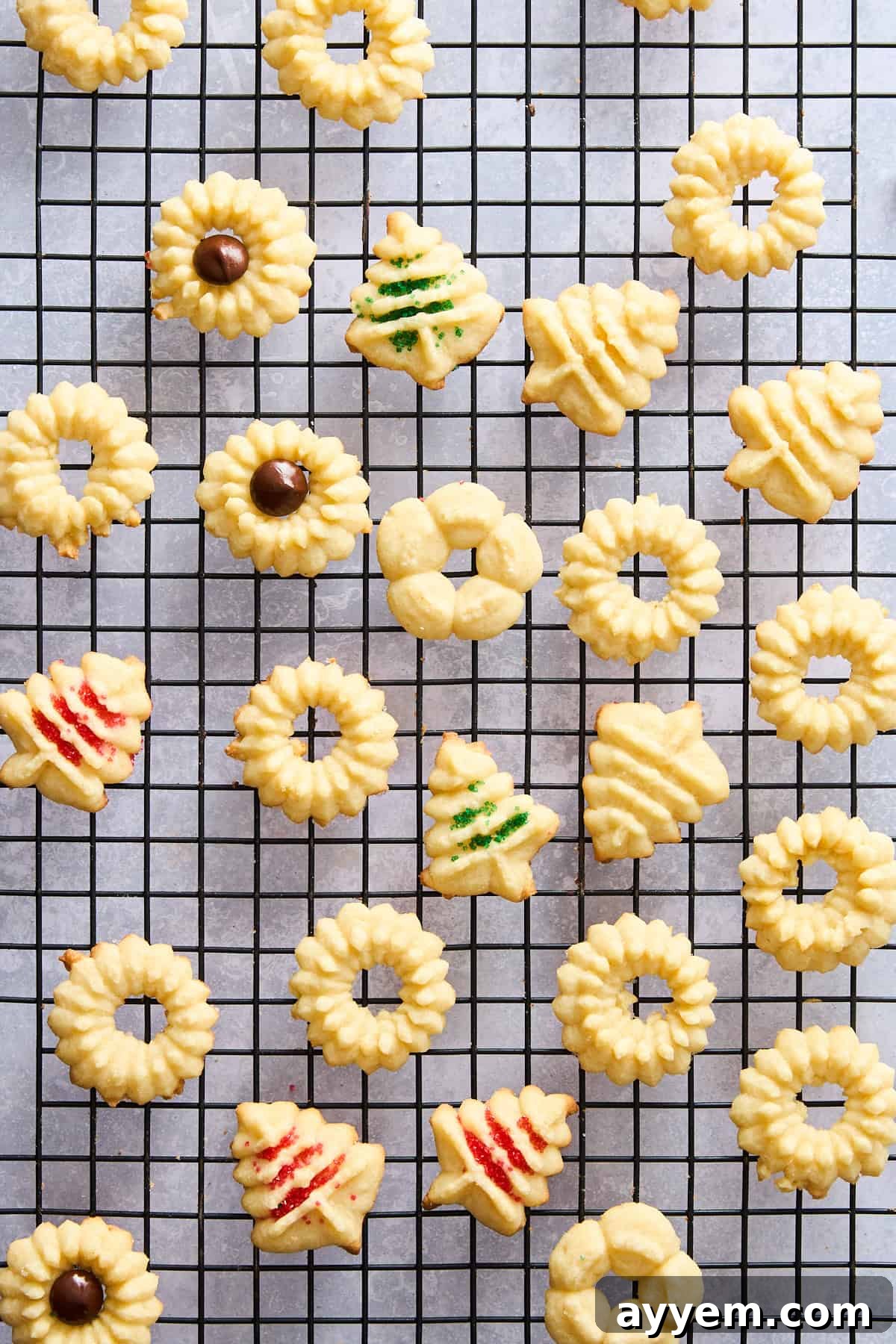 Assorted spritz cookies in various shapes cooling on a wire rack, ready for decoration or serving.