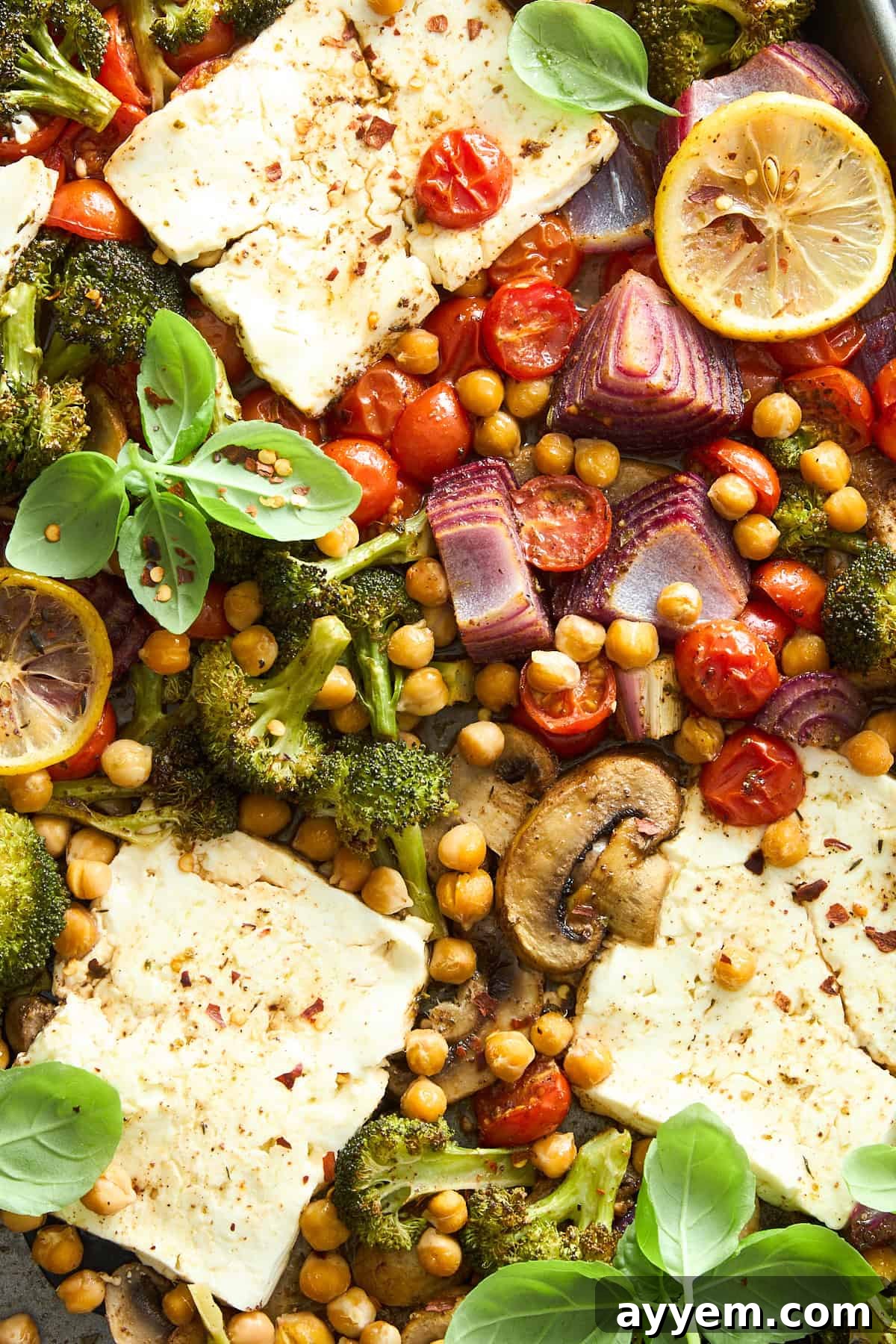A close-up view of the perfectly roasted sheet pan feta and veggies, with crispy chickpeas and melted feta.