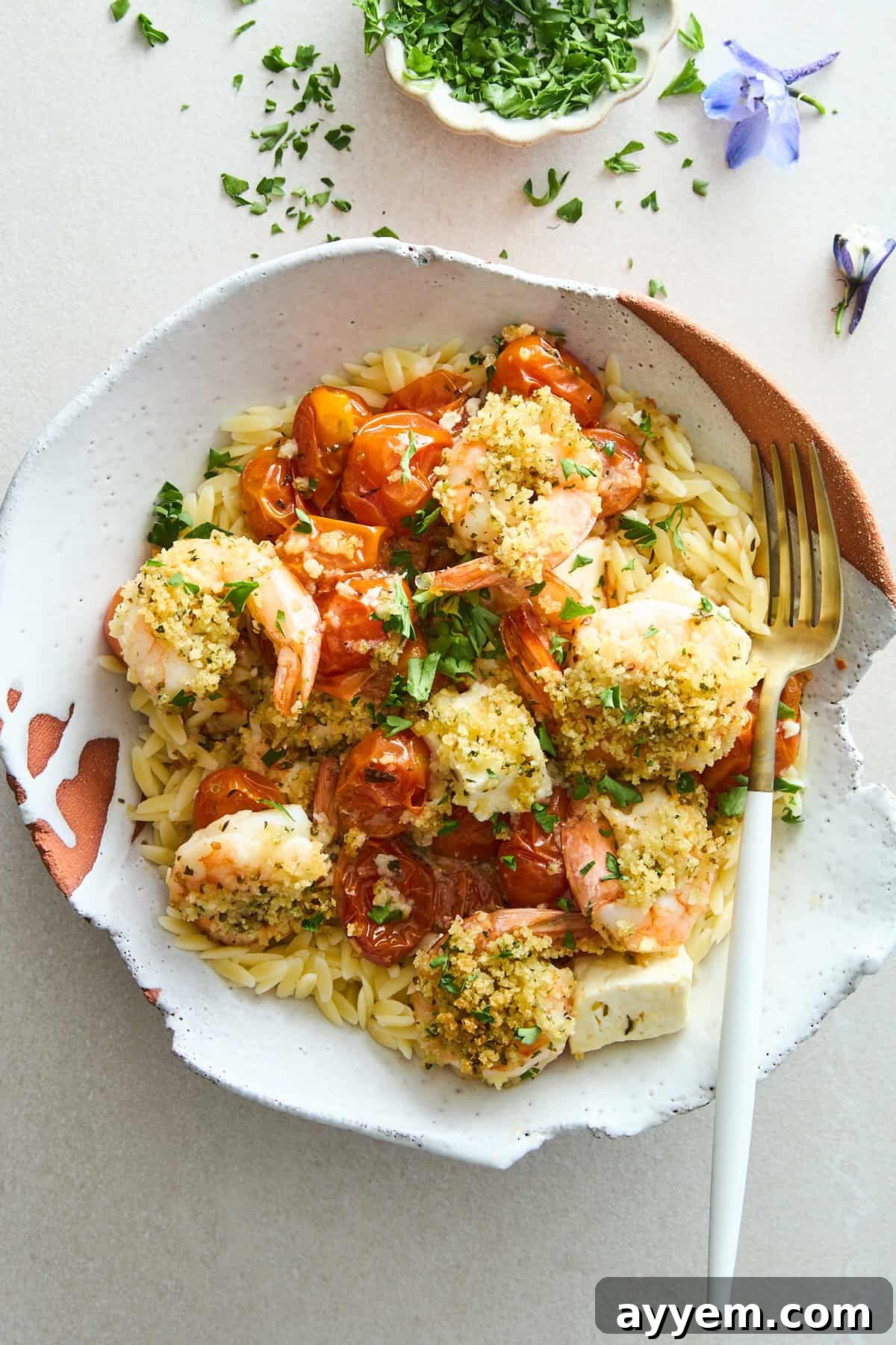 A bowl of Panko Shrimp and Feta Bake served over orzo pasta, garnished with fresh parsley.