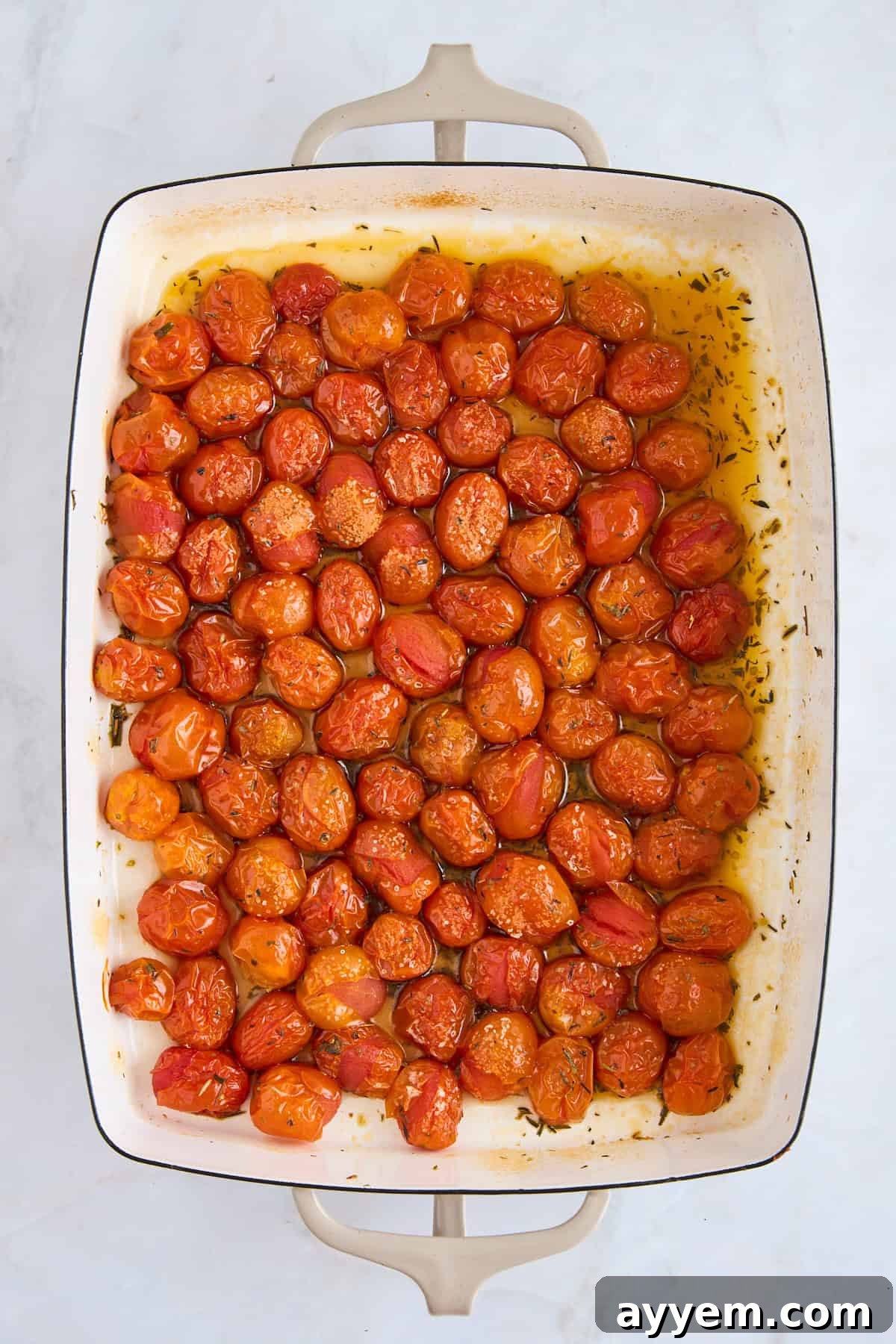 Roasted cherry tomatoes in a baking dish, softened and bursting with juices.