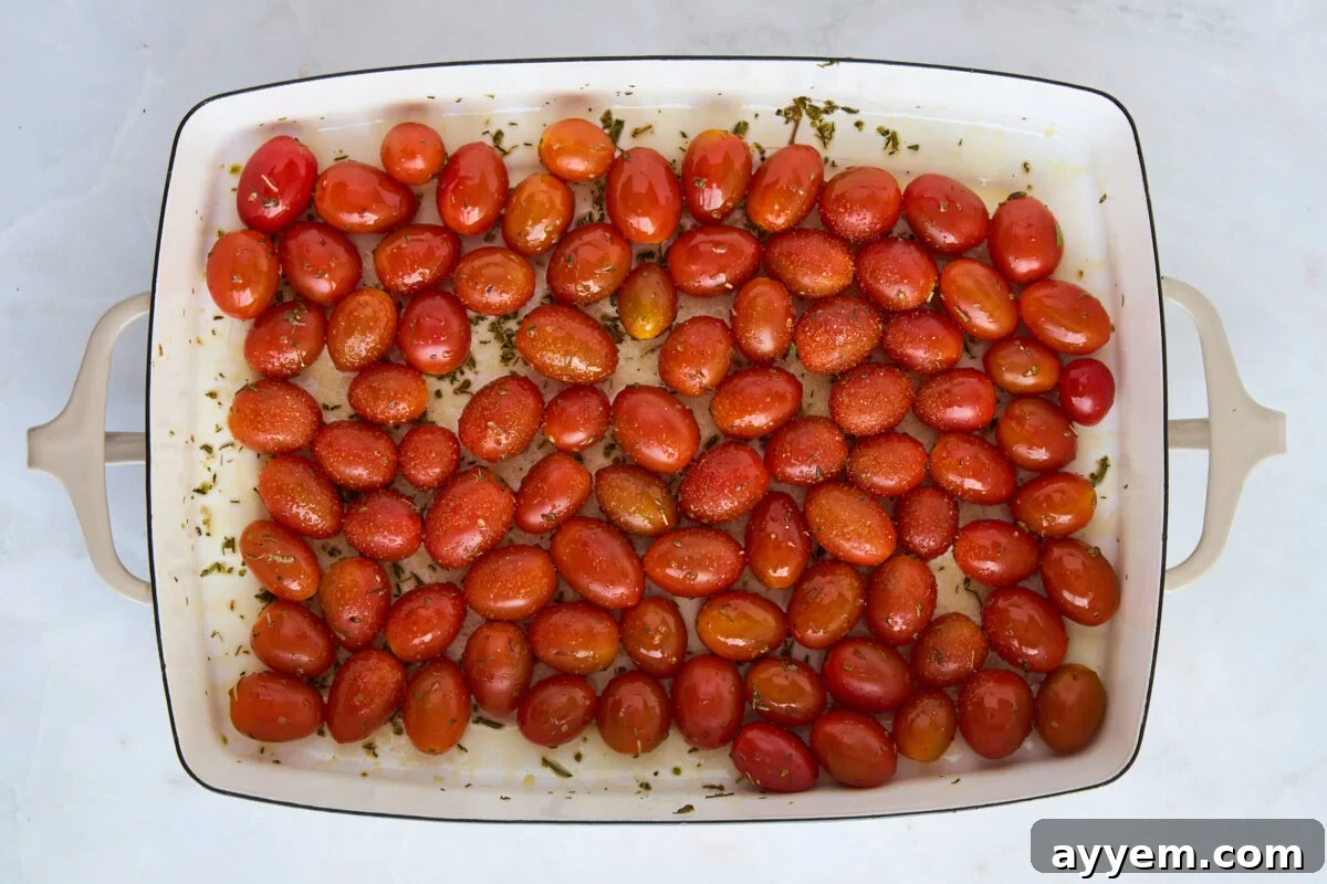 Seasoned cherry tomatoes in a baking dish, ready for roasting.