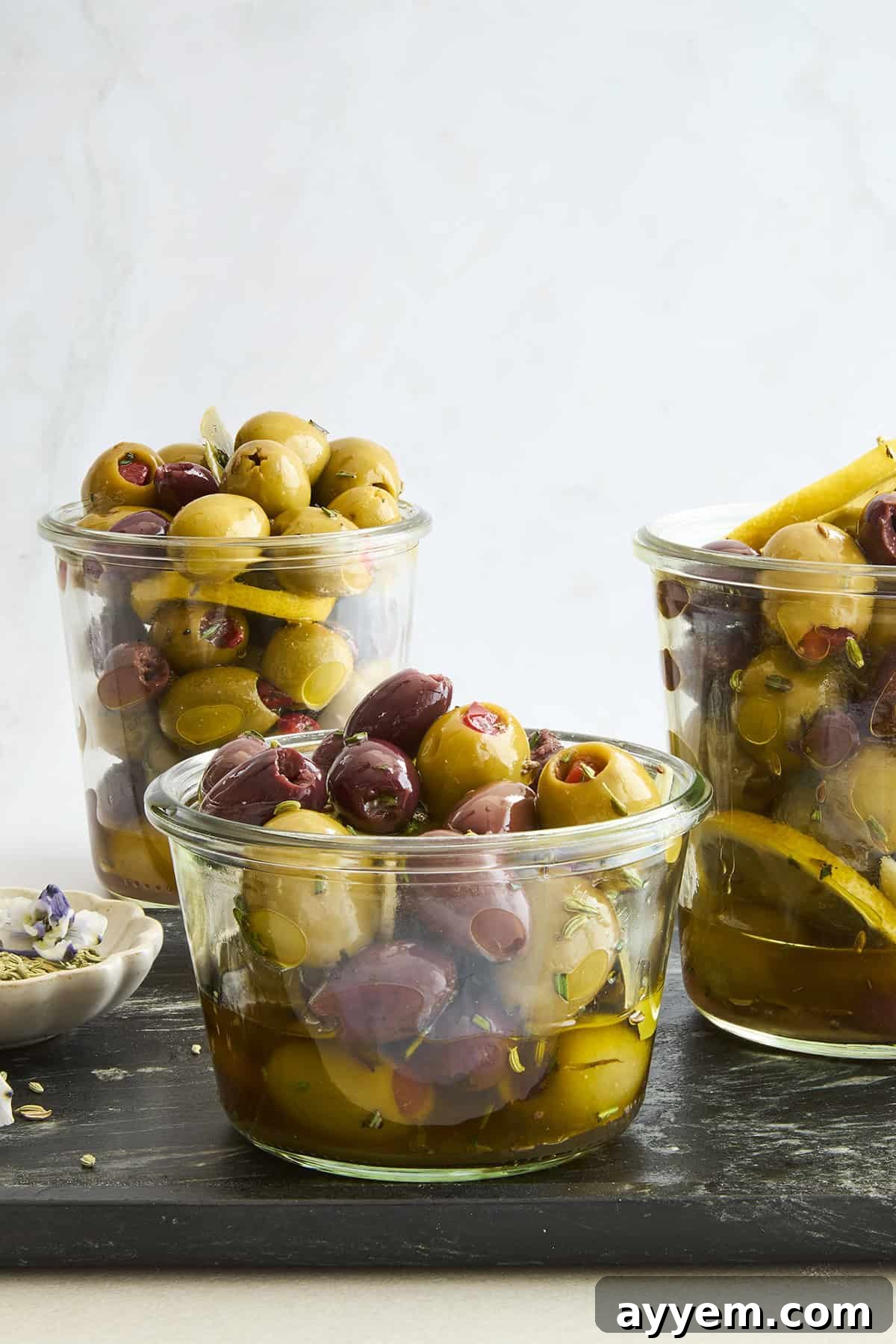 Jars of green and black marinated olives, showcasing the vibrant colors and fresh herbs.