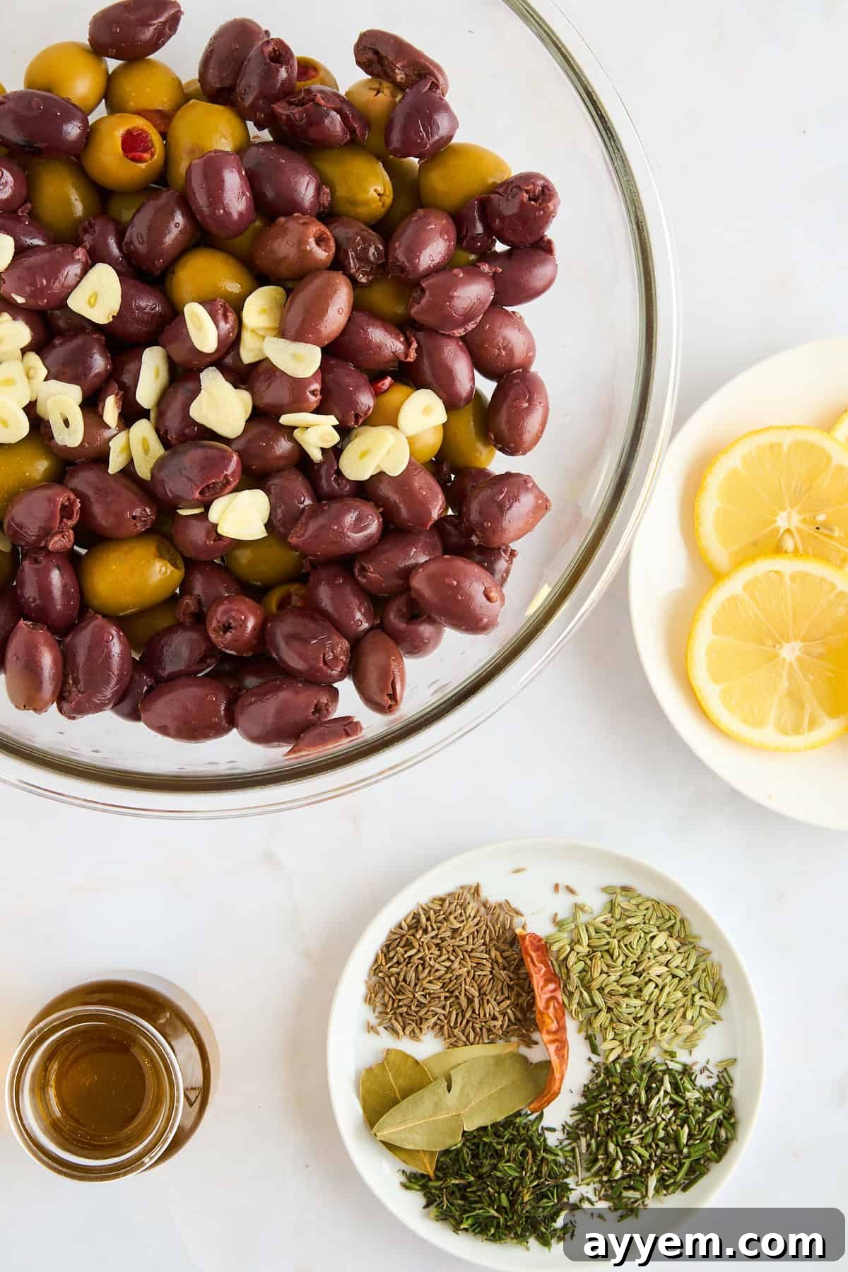 A bowl of olives, seasonings, lemons, and olive oil, ready for marinating. 