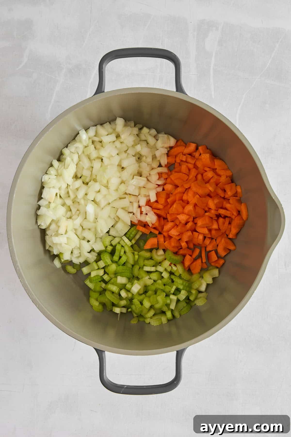 Diced onions, celery, and carrots waiting to be sautéed in a pot.