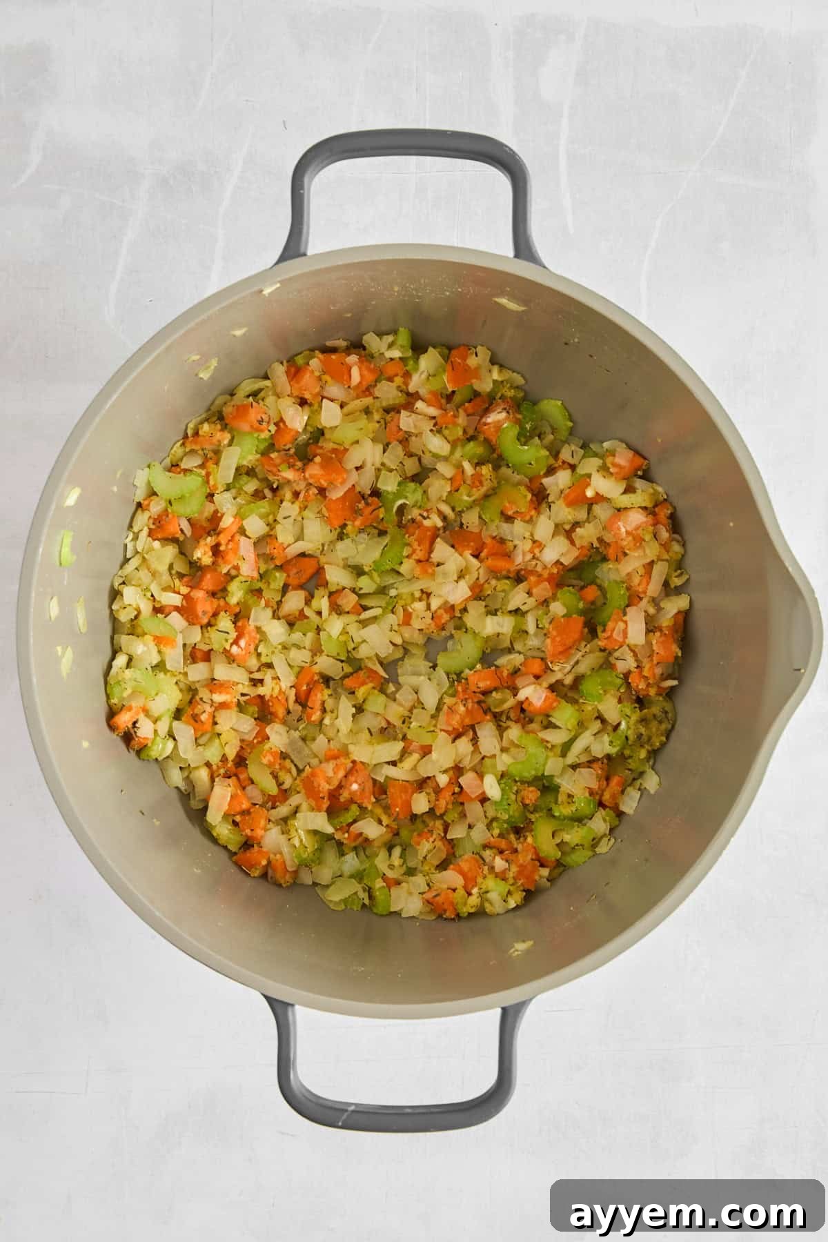 Onions, carrots, and celery gently sautéing in olive oil in a pot.
