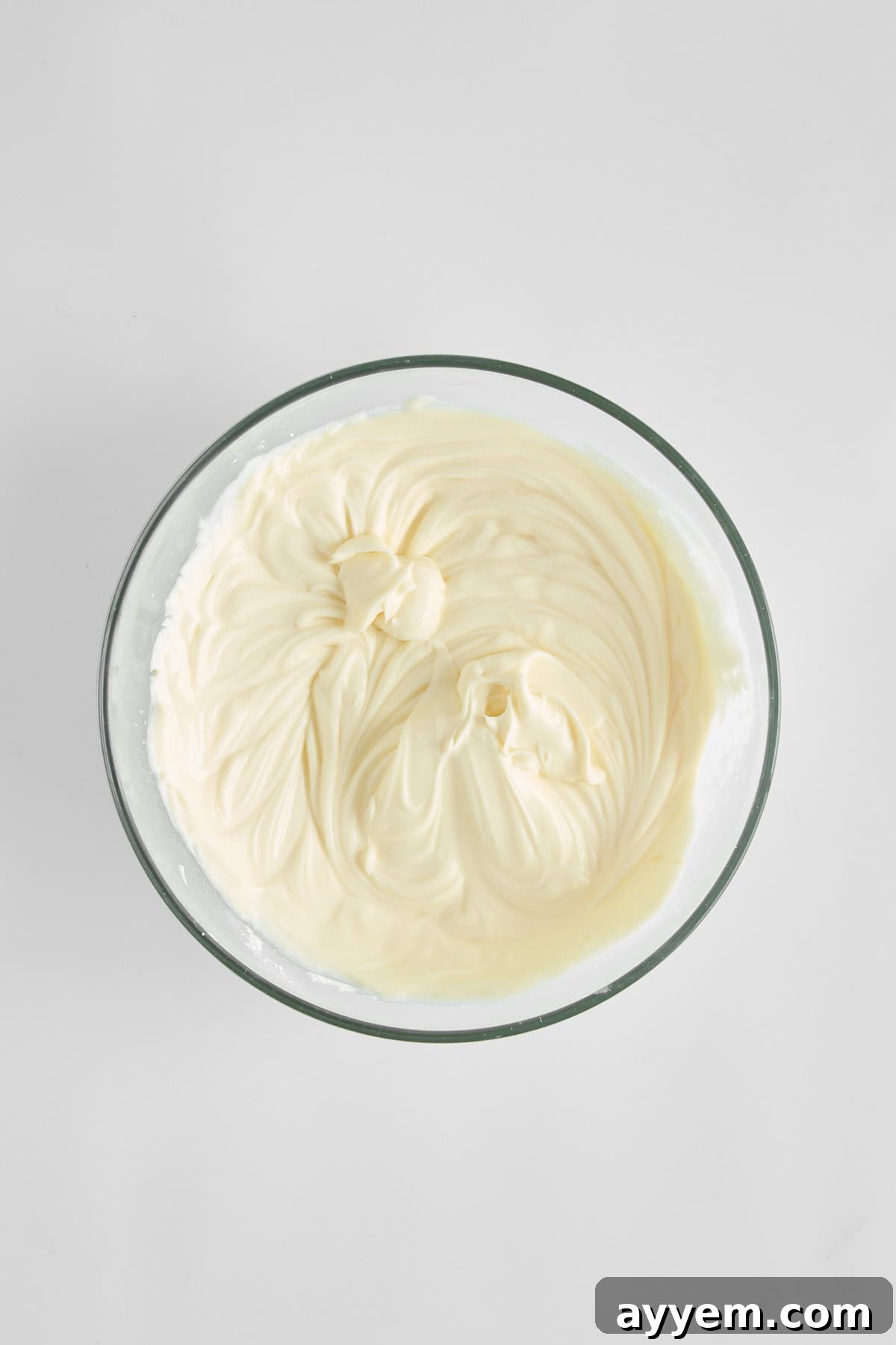 Whipped powdered sugar, mascarpone cheese, and Greek yogurt in a bowl, showing the smooth, blended dressing consistency.