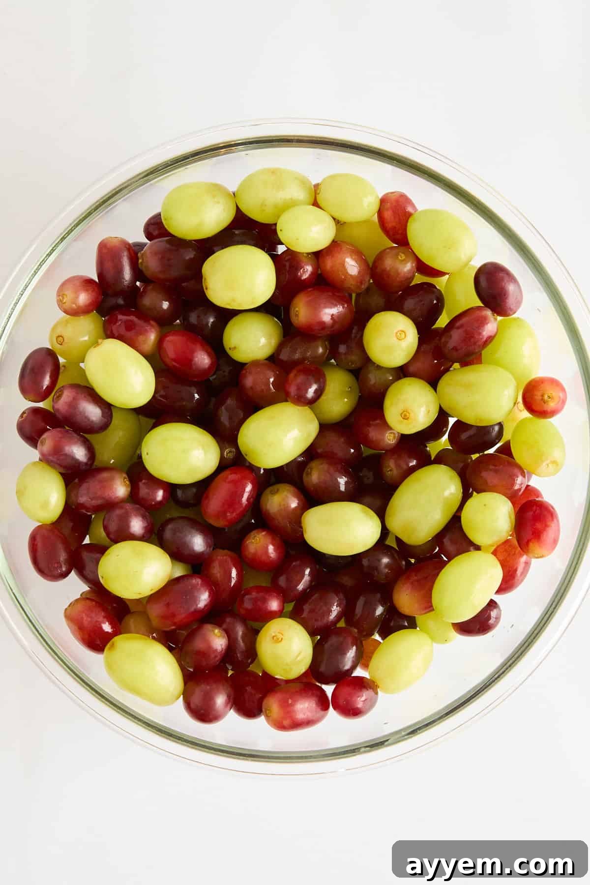 Vibrant red and green seedless grapes meticulously washed and dried in a large bowl, forming the colorful base of the salad.