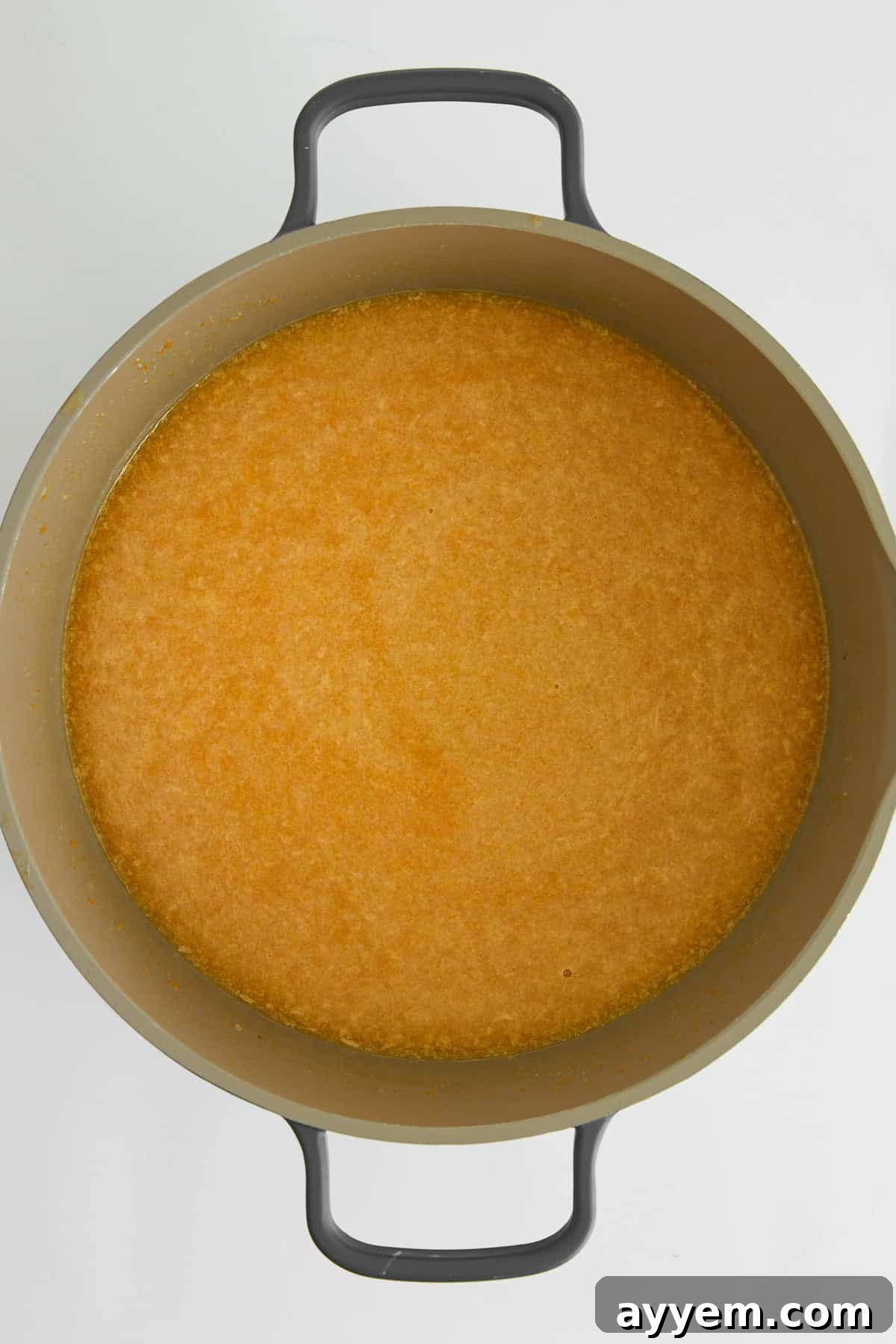 A large pot filled with rich, golden pastina soup broth, ready for the addition of tiny pasta.
