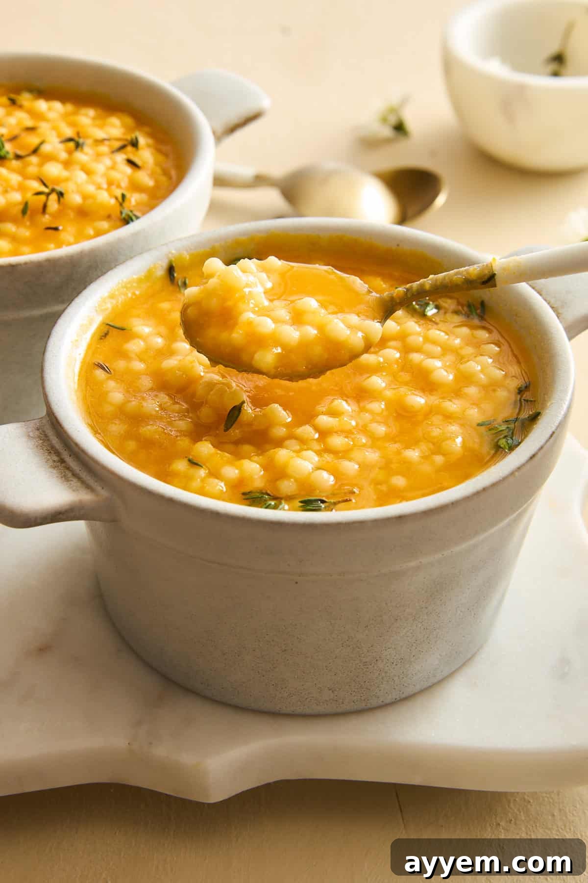 A spoon lifting a perfect bite of pastina soup from a bowl, showcasing the tiny pasta and rich broth.