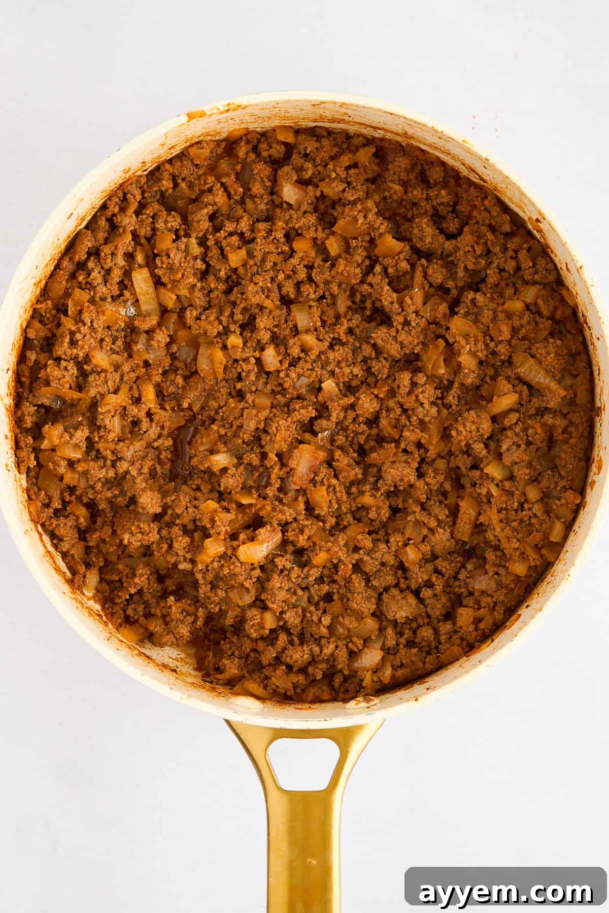 Cooked ground beef with tomato paste, spices, and onions simmering in a pot.