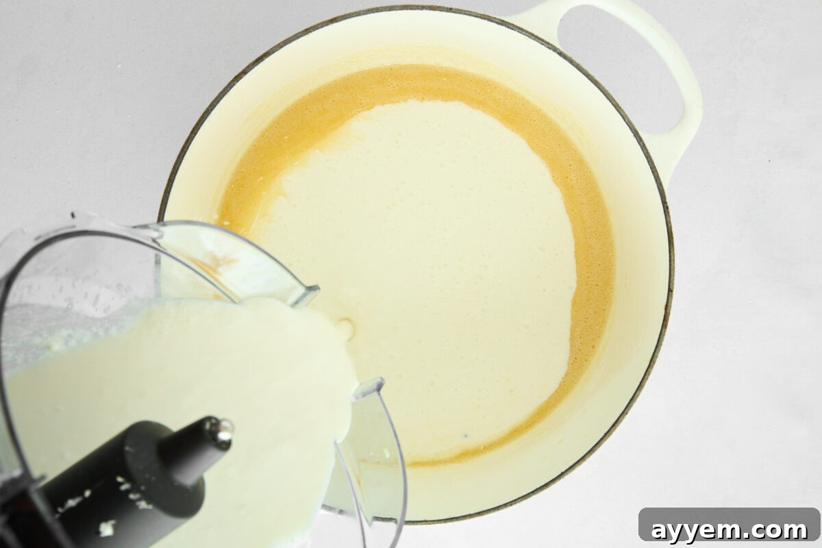 Blended cottage cheese sauce being combined with melted butter and flour in a skillet.