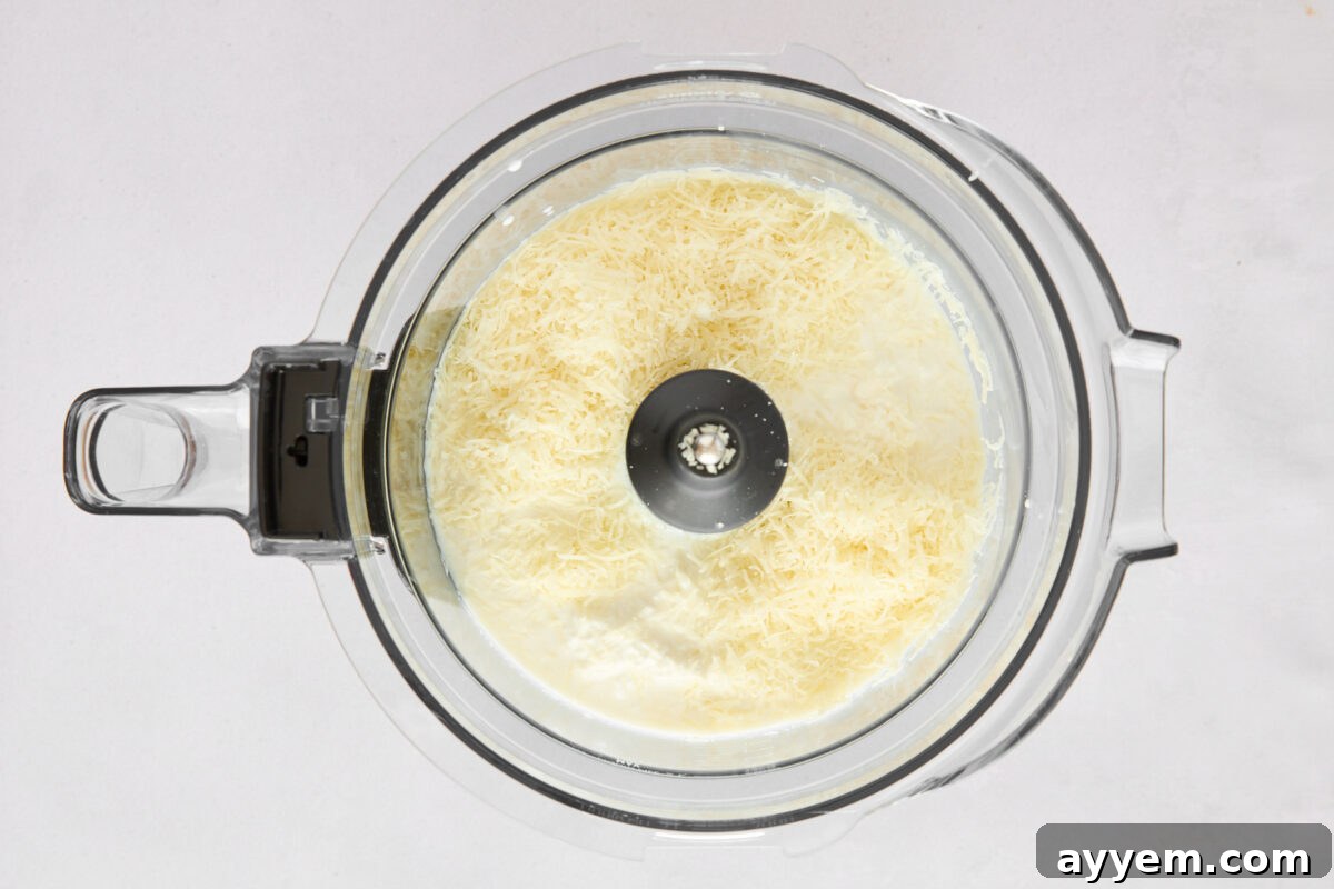 Cottage cheese, milk, Parmesan, and garlic blending in a food processor to form a smooth sauce.