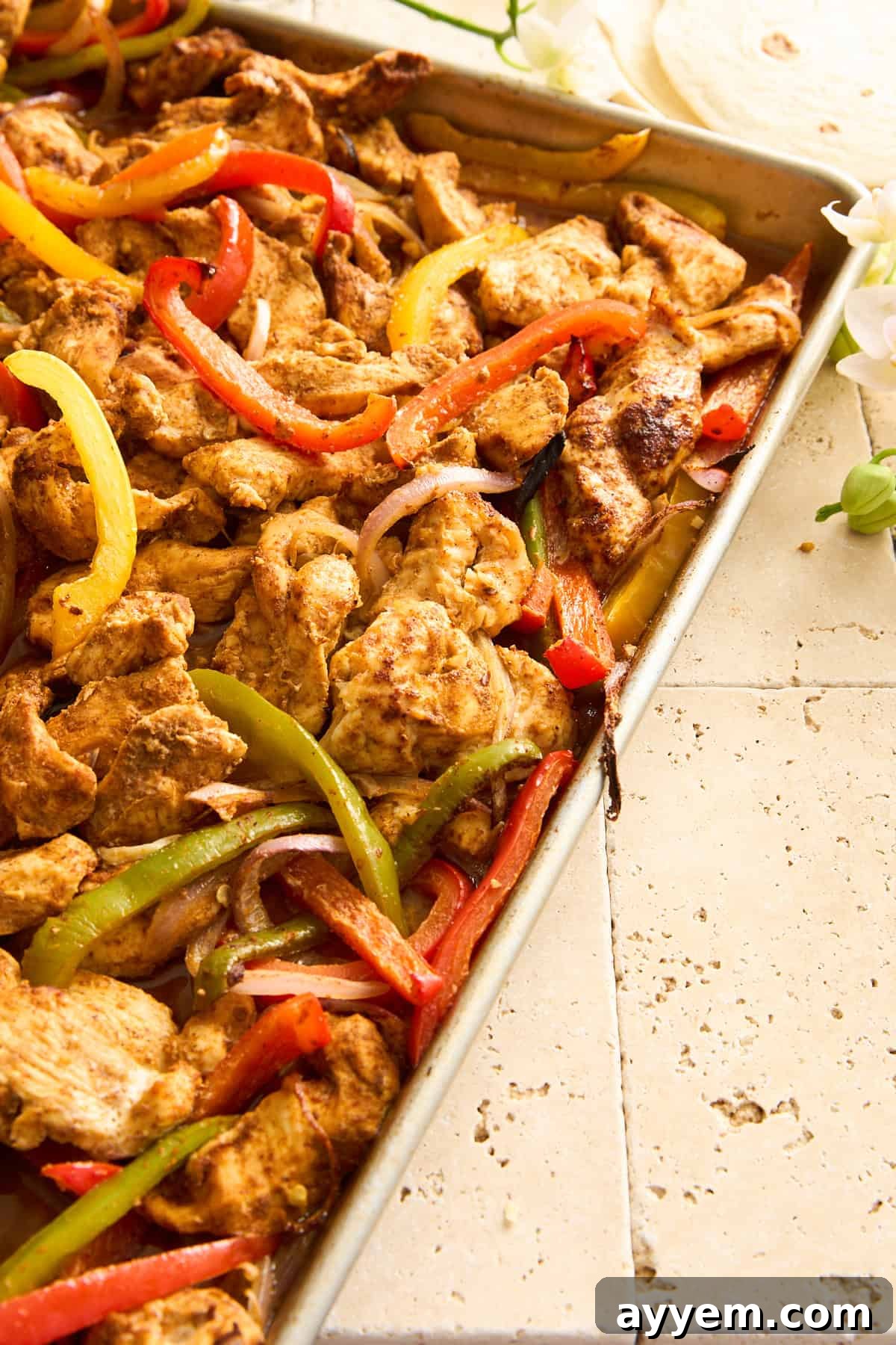 Close-up of freshly cooked Sheet Pan Chicken Fajitas, perfectly browned and tender, topped with a squeeze of fresh lime, ready to be served.