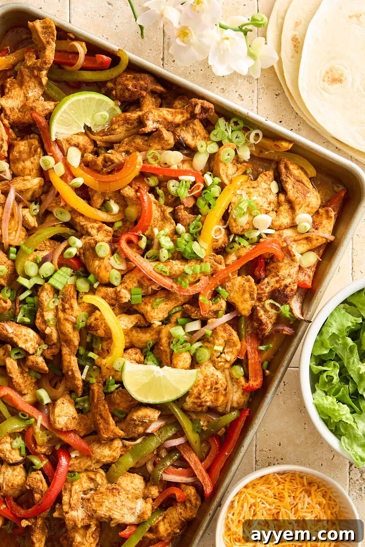 Sheet pan chicken fajitas topped with lime wedges.