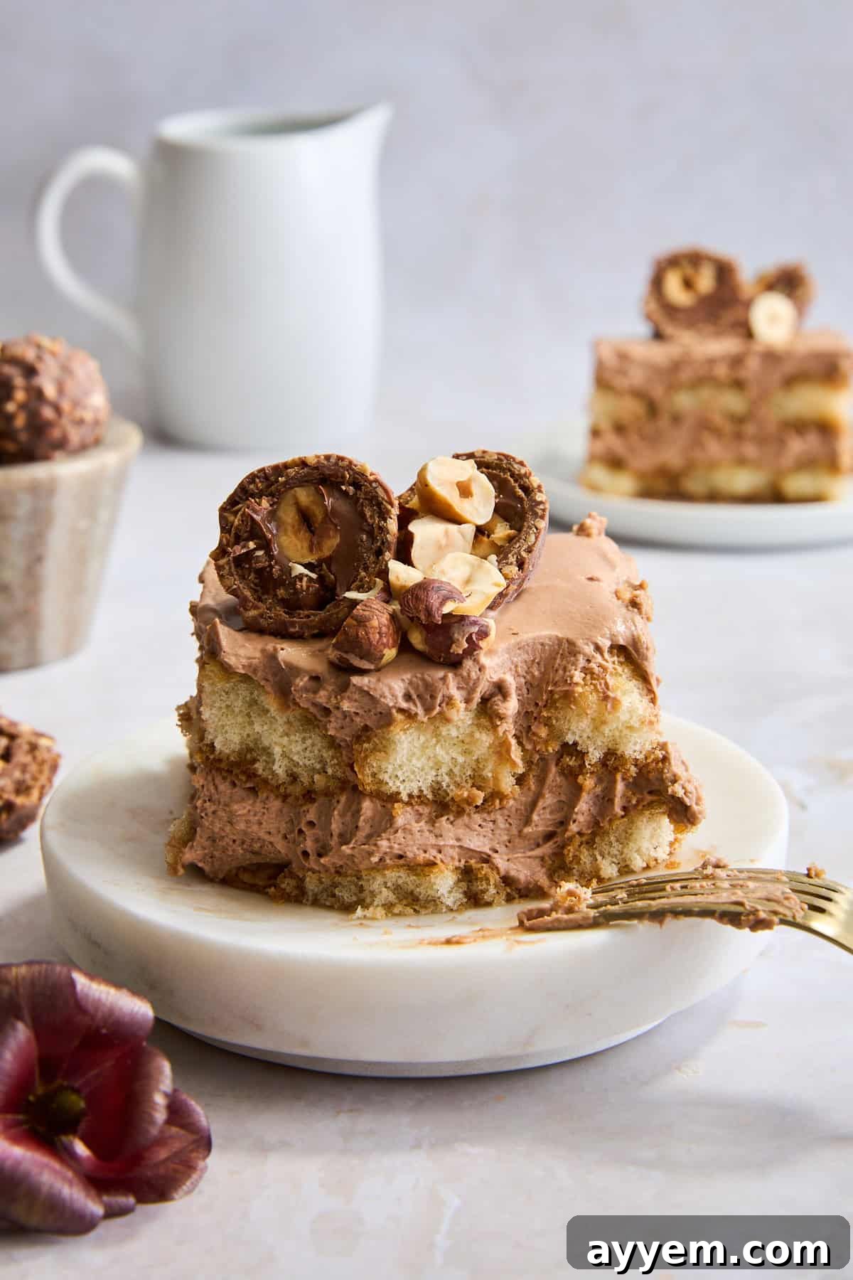 A slice of Nutella tiramisu on a plate with a bite missing and a fork balanced on the edge. 