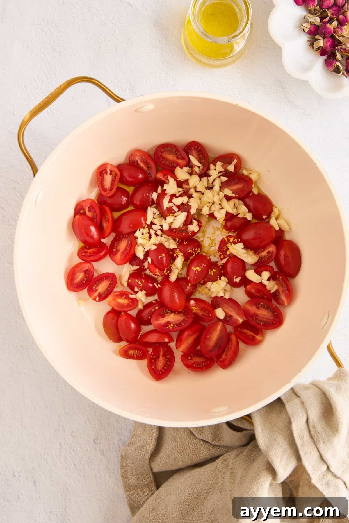 Fresh grape tomatoes and minced garlic ready to be sautéed in a large pasta pot, illustrating the start of the cooking process.