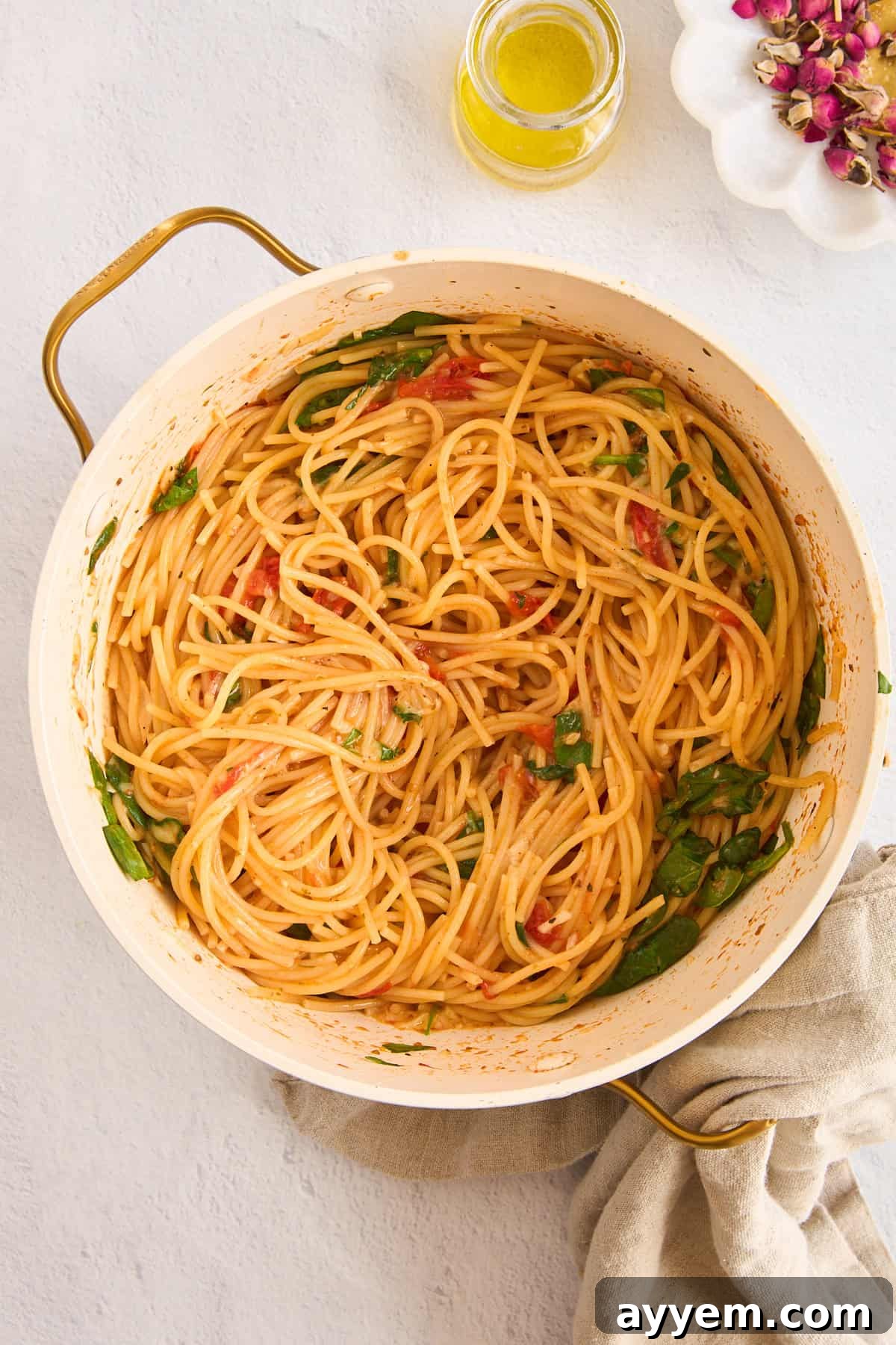 A close-up of the finished one-pot Meghan Markle pasta in a pot, steaming and ready to serve, with wilted spinach and cherry tomatoes visible.