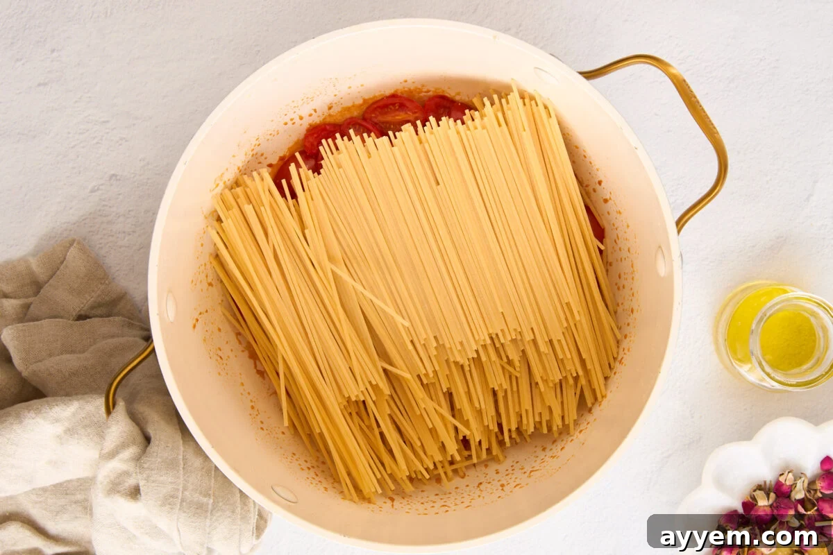 Pasta in a pot with tomatoes and garlic.
