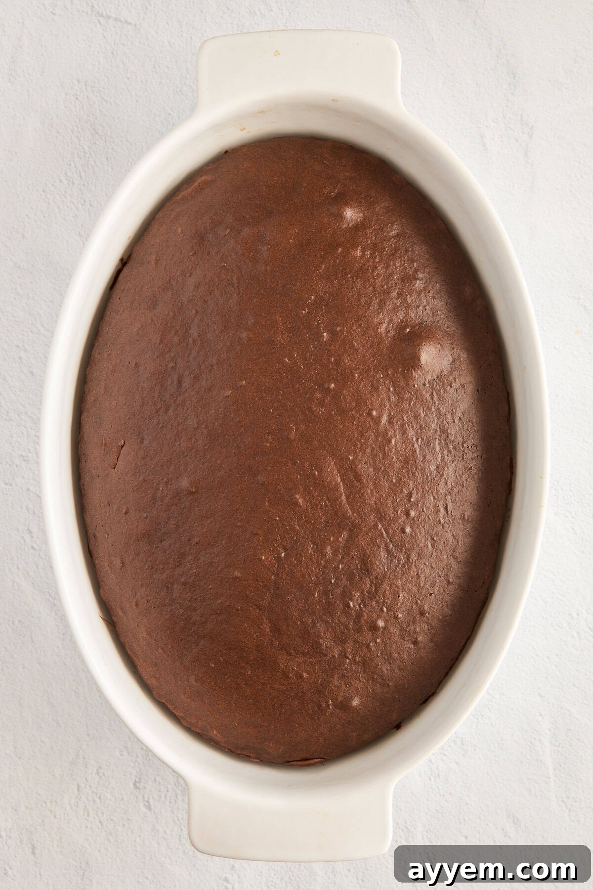 Cake being poked with a fork to absorb chocolate milk.