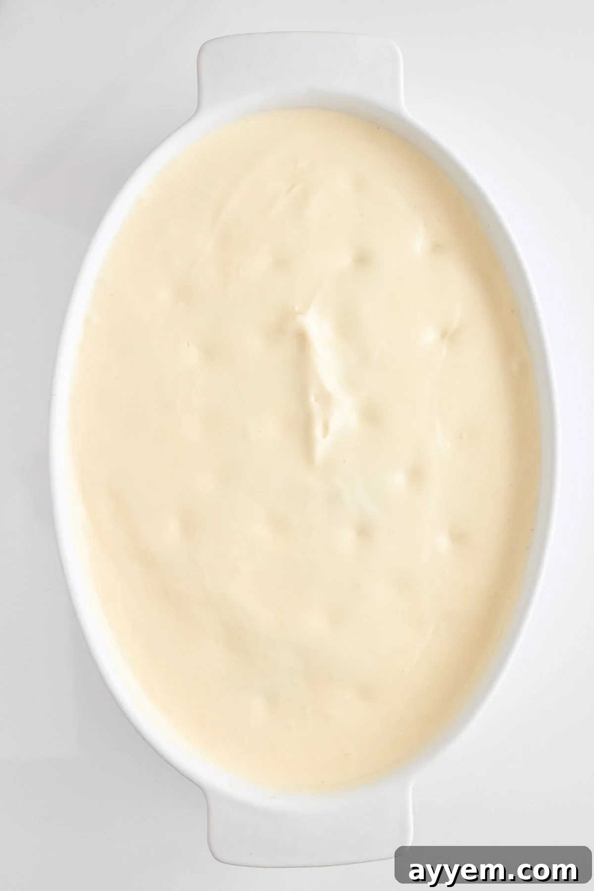 Creamy mascarpone filling being spread over the chocolate cake.