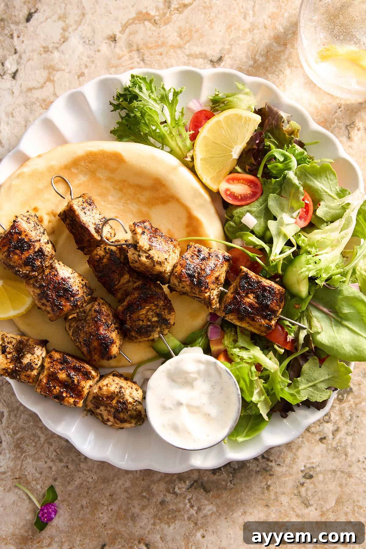 A plate of Mediterranean chicken skewers with pita bread and a side salad, ready to be enjoyed.