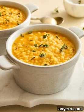 A ramekin of pastina soup topped with fresh rosemary.
