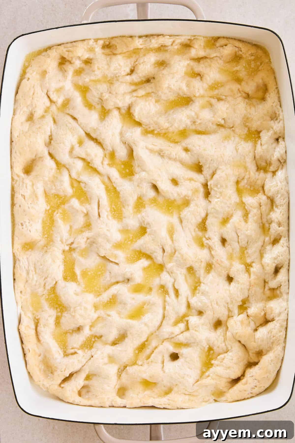 Dimpled focaccia dough generously drizzled with olive oil, before adding the topping.