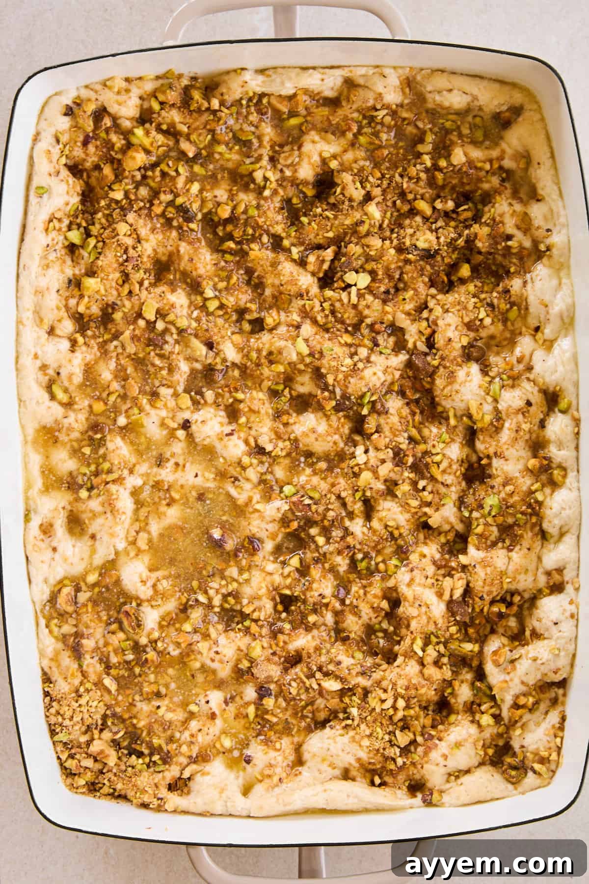 Unbaked baklava dessert focaccia, topped with the sweet spiced nut mixture, ready for the oven.