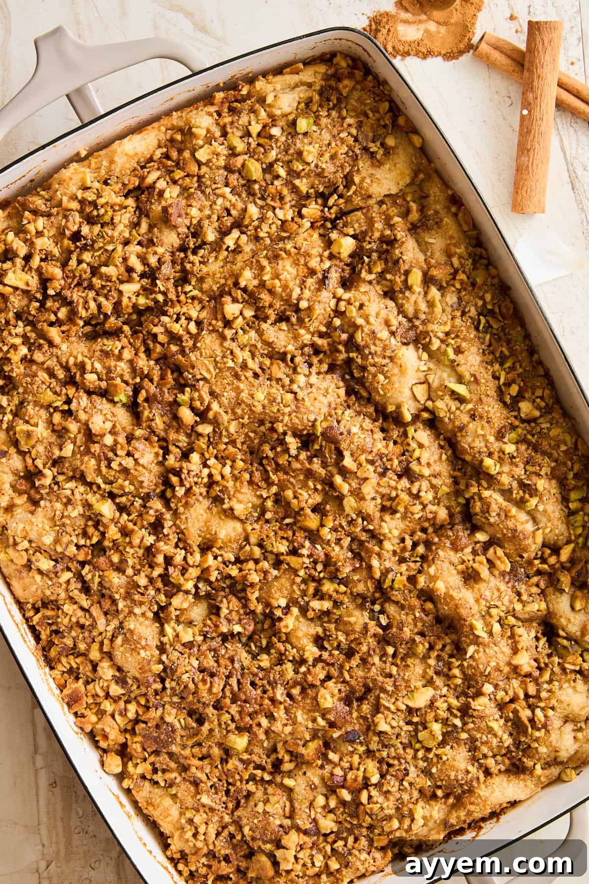 Freshly baked Baklava Dessert Focaccia in a baking dish, glistening with honey syrup and topped with toasted nuts.