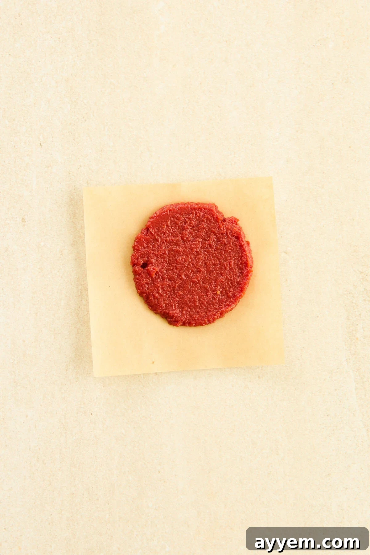 A perfectly formed disc of frozen tomato paste on a piece of parchment paper.