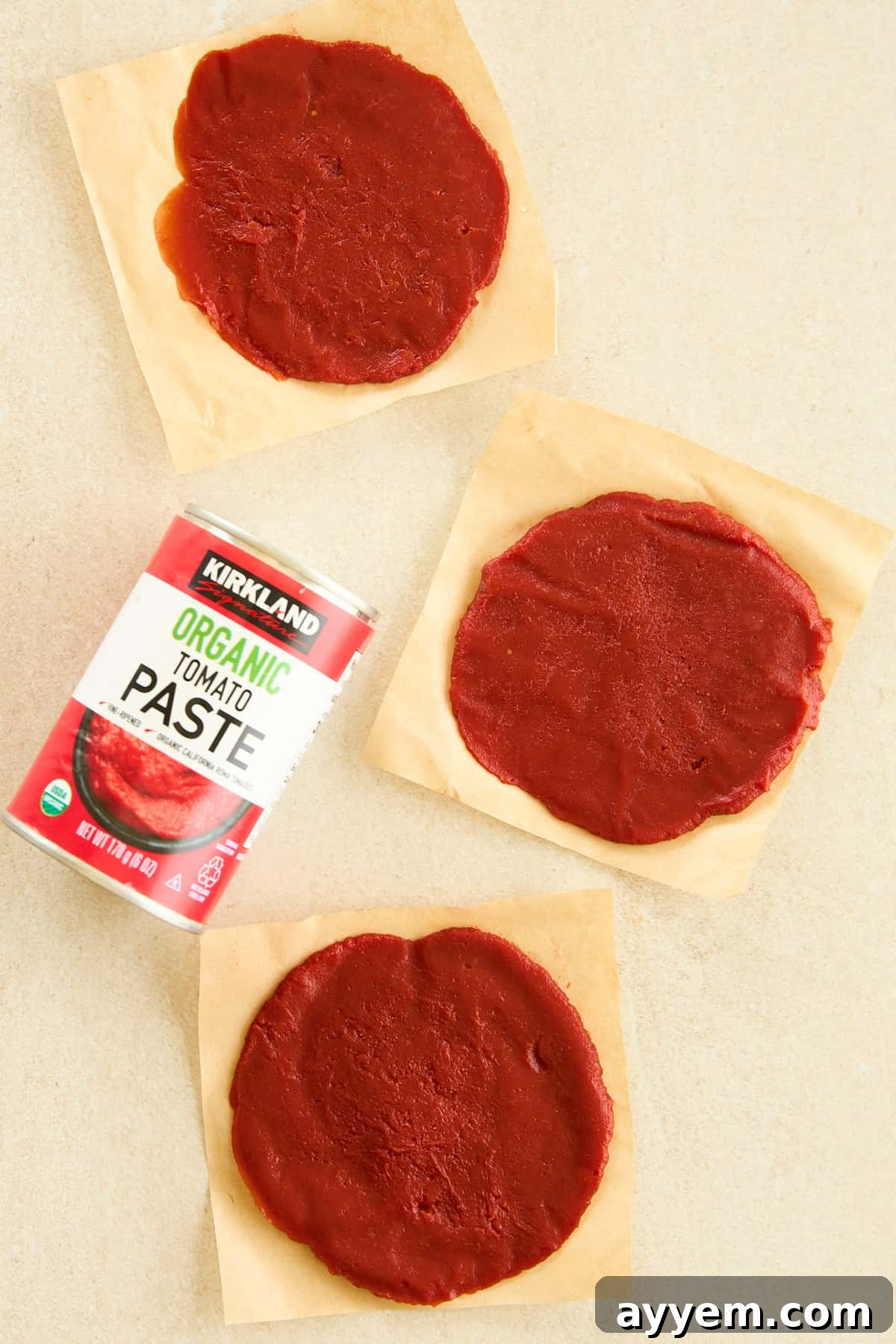 Frozen tomato paste discs on parchment paper next to a can, illustrating the finished product.