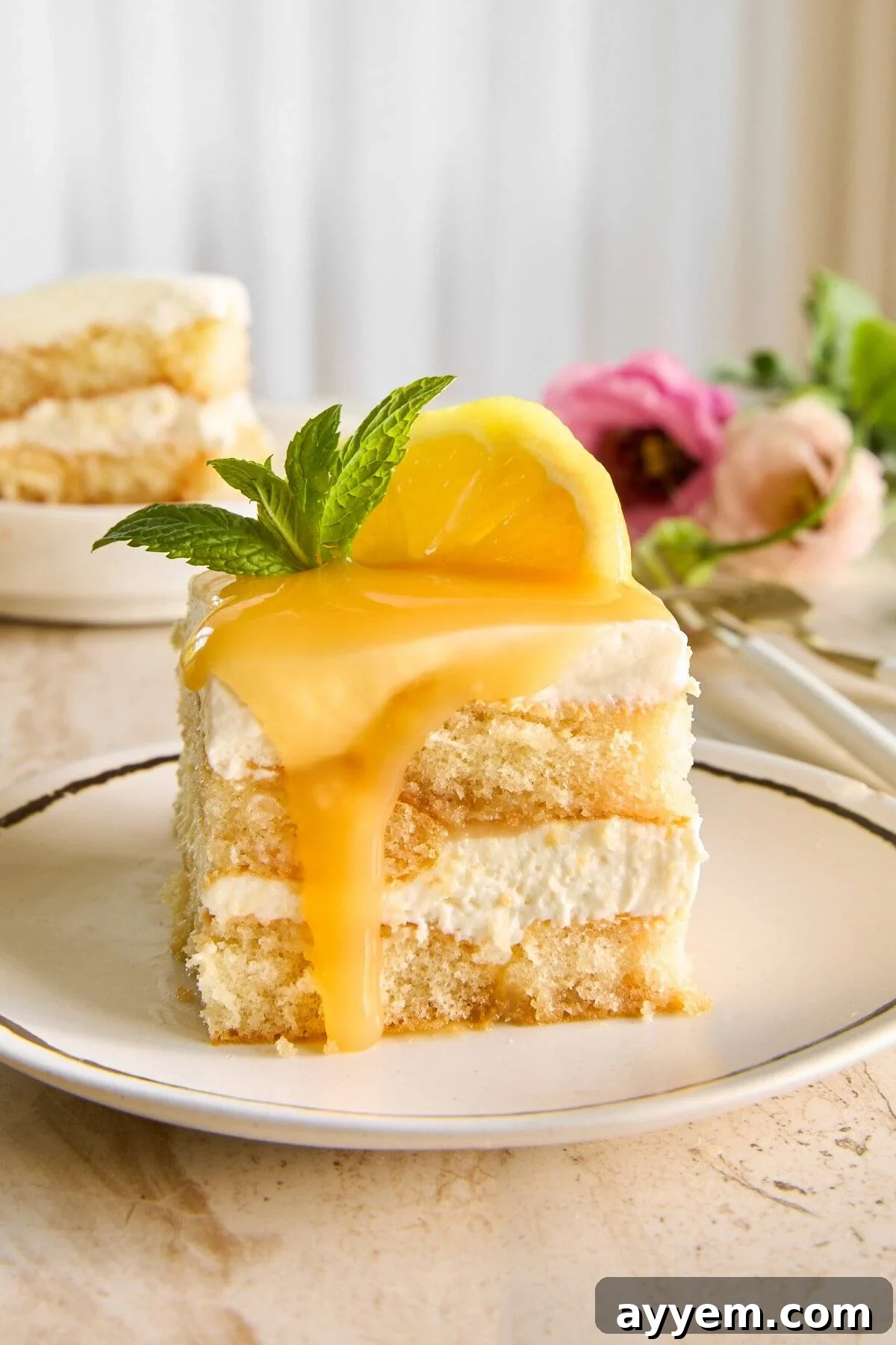 A slice of lemon tiramisu topped with lemon curd on a white plate.