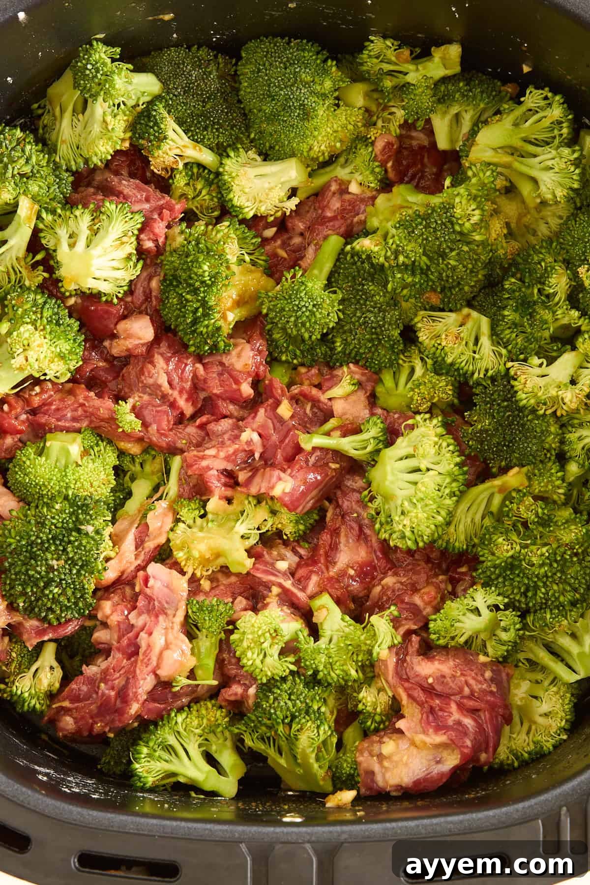 Raw air fryer beef and broccoli in an air fryer basket. 