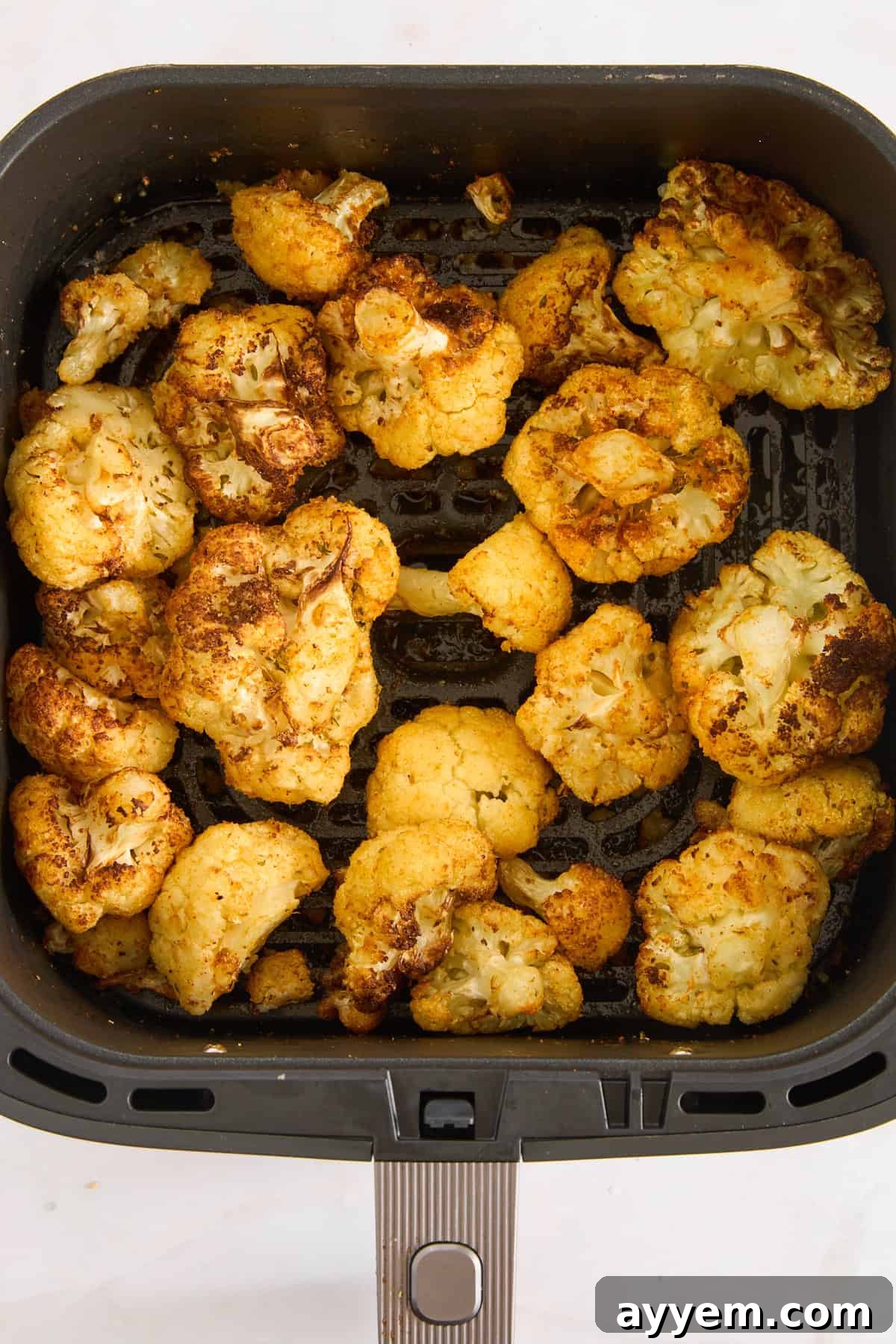 Perfectly air-fried cauliflower, golden brown and crispy, resting in an air fryer basket.