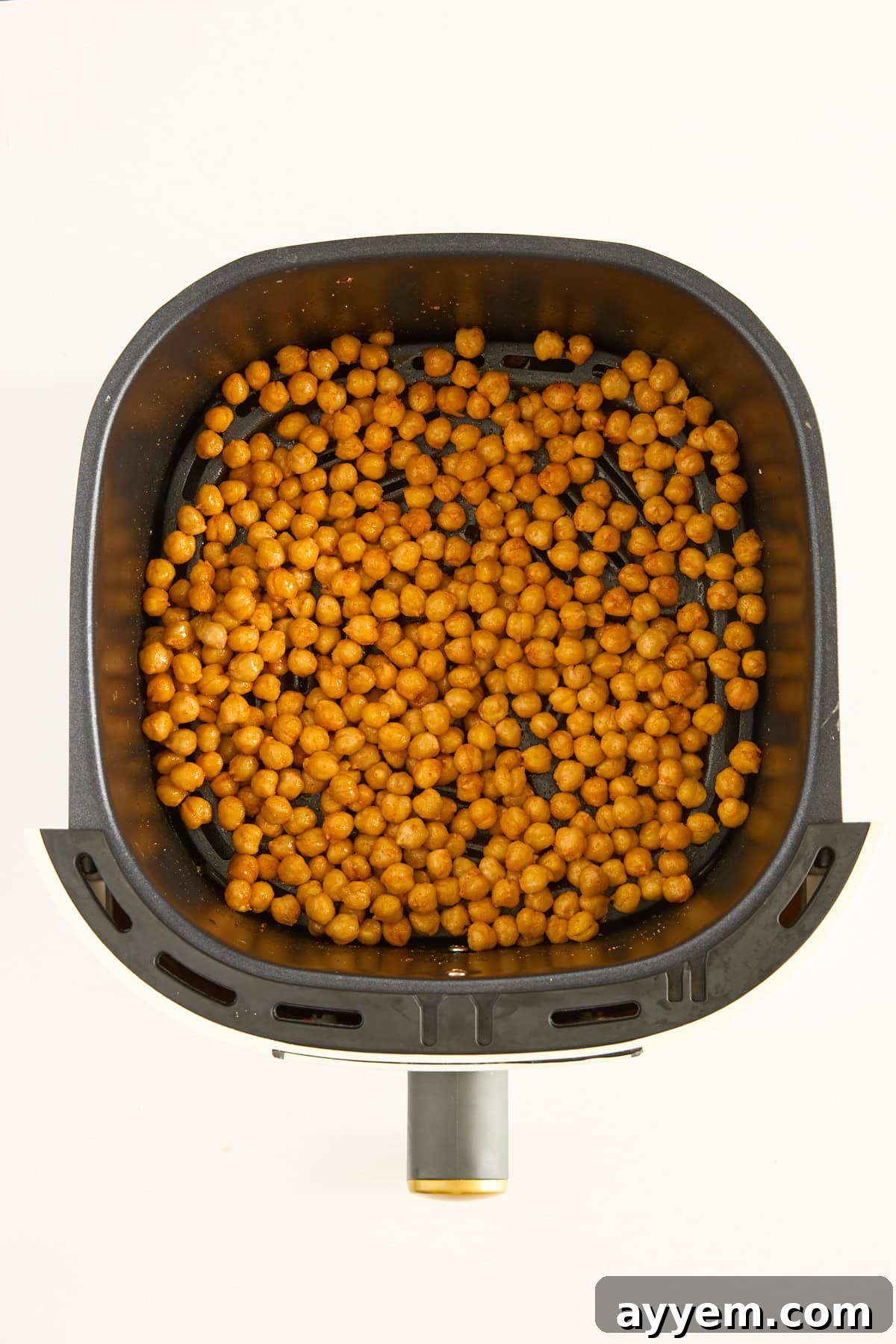 Close-up of golden, crispy air fryer chickpeas in an air fryer basket after cooking.