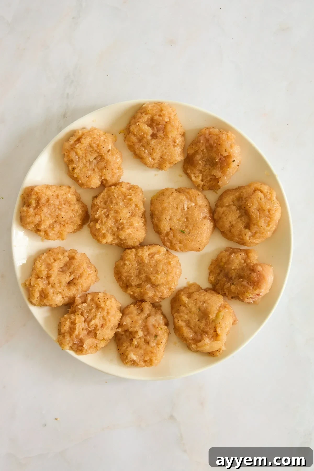 Raw chicken nuggets, perfectly shaped and coated with breadcrumbs, waiting to be air-fried.