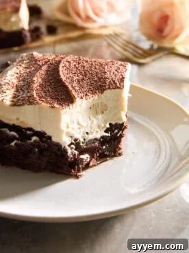 A tiramisu brownie slice on a plate with a corner bite missing.