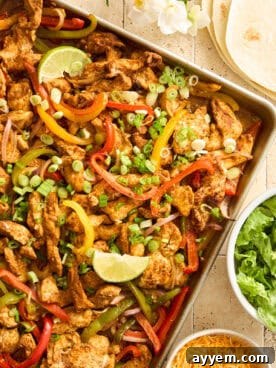 Sheet pan chicken fajitas topped with lime wedges.
